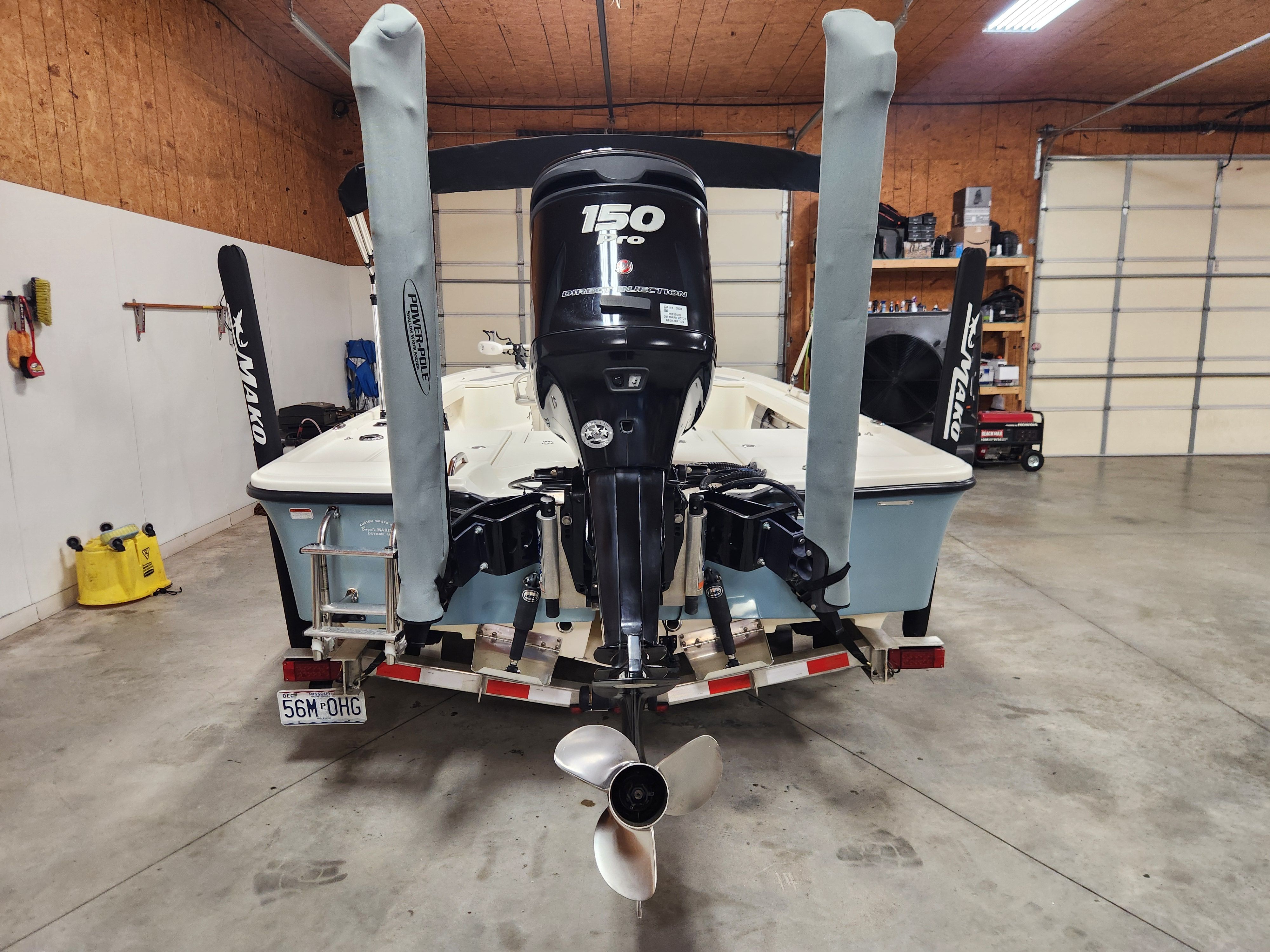 Rear view of a Mako 21 LTS boat in a garage, featuring a 150 HP engine.