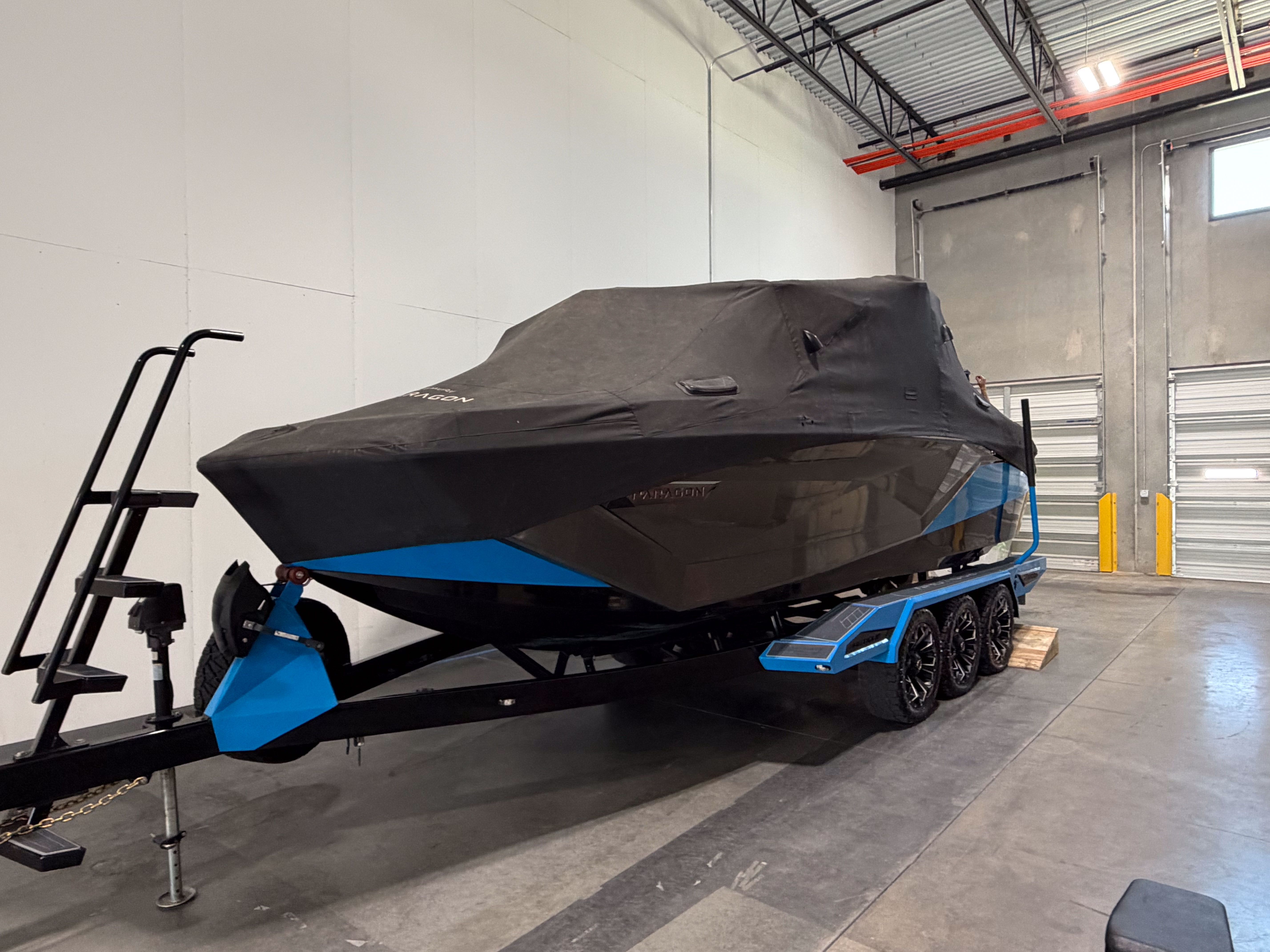 A covered boat on a trailer inside a warehouse.