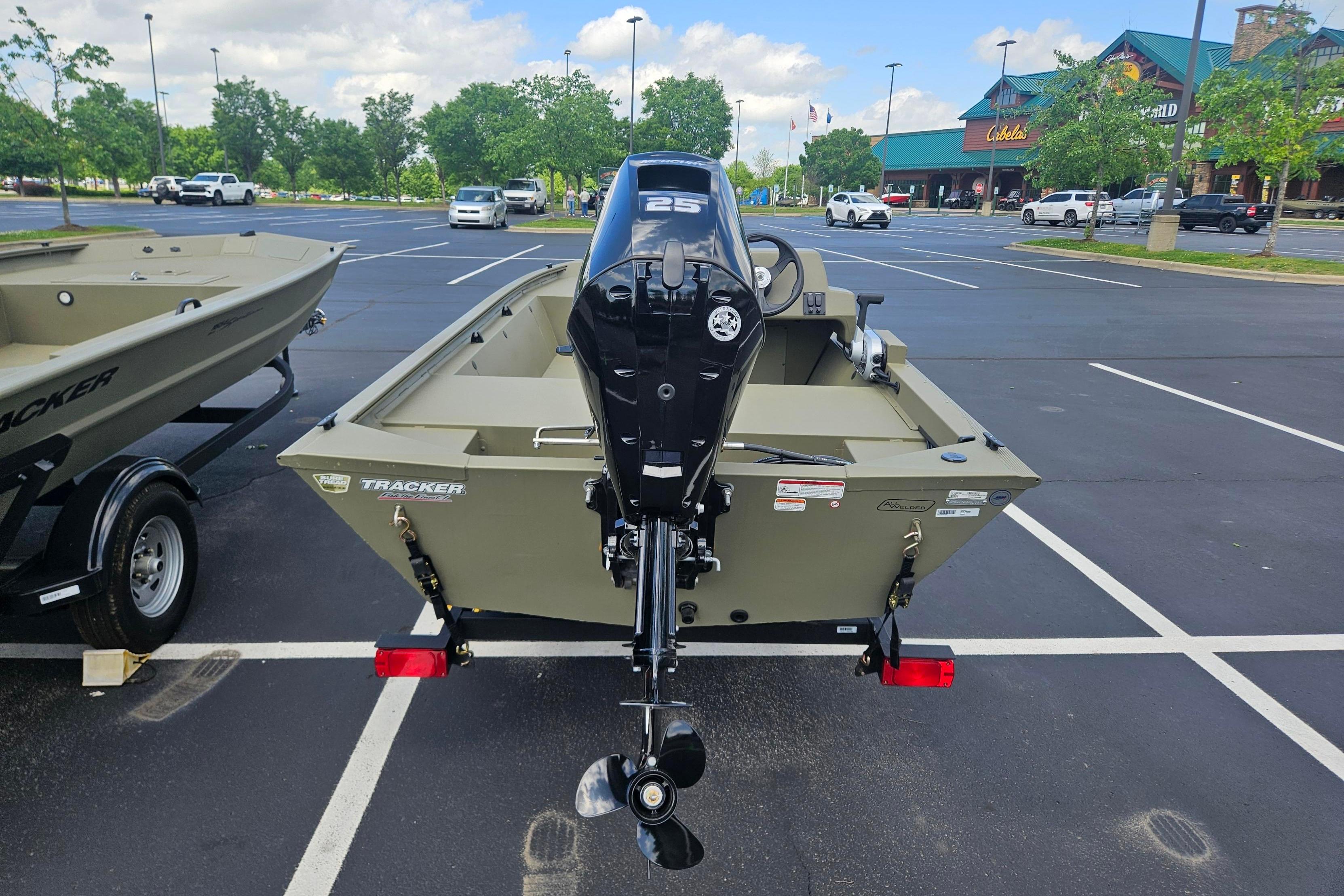 2026 Tracker Grizzly 1648 SC boat with outboard motor in parking lot.