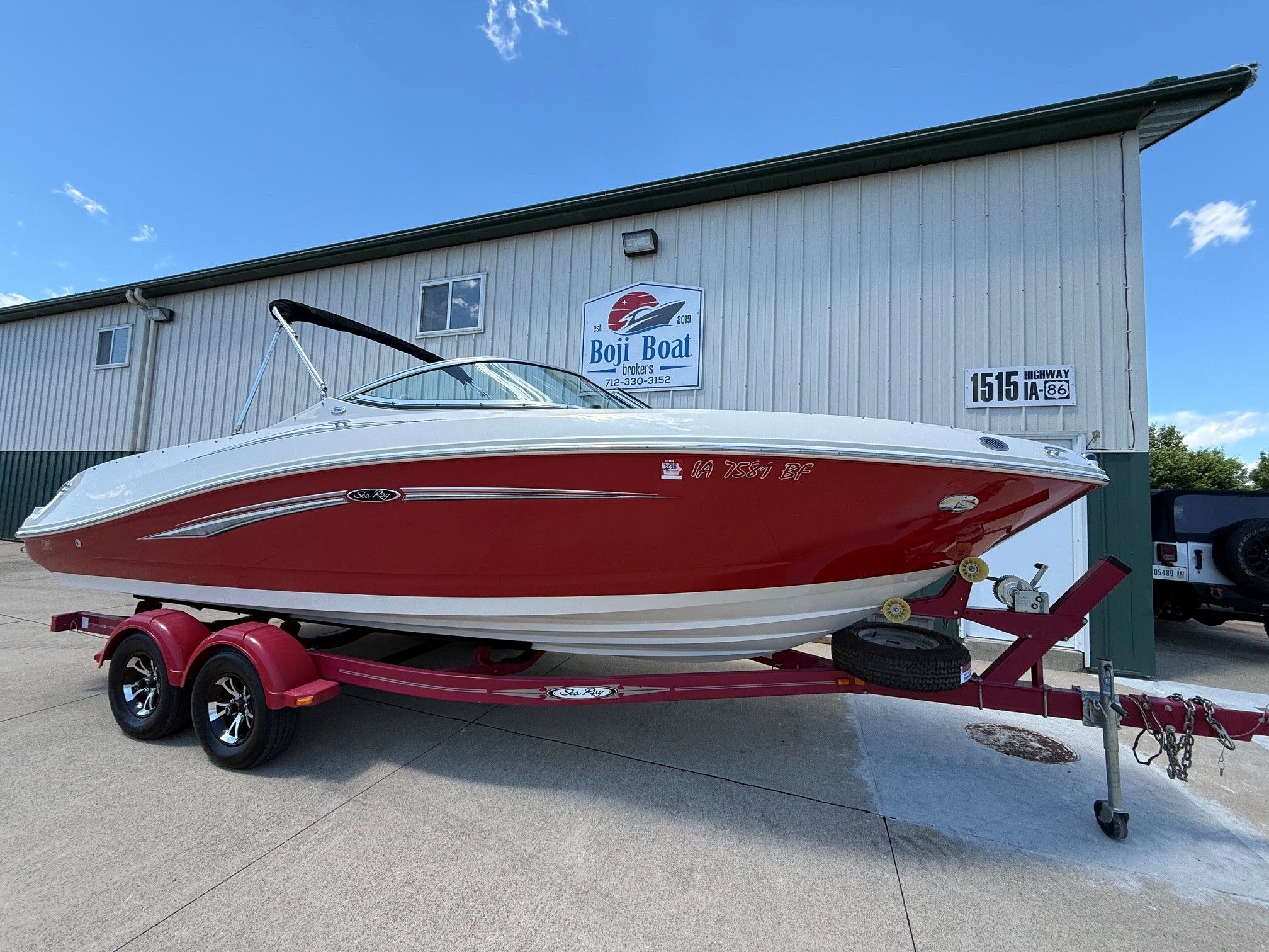 2007 Sea Ray 230 Select boat on trailer in front of building.