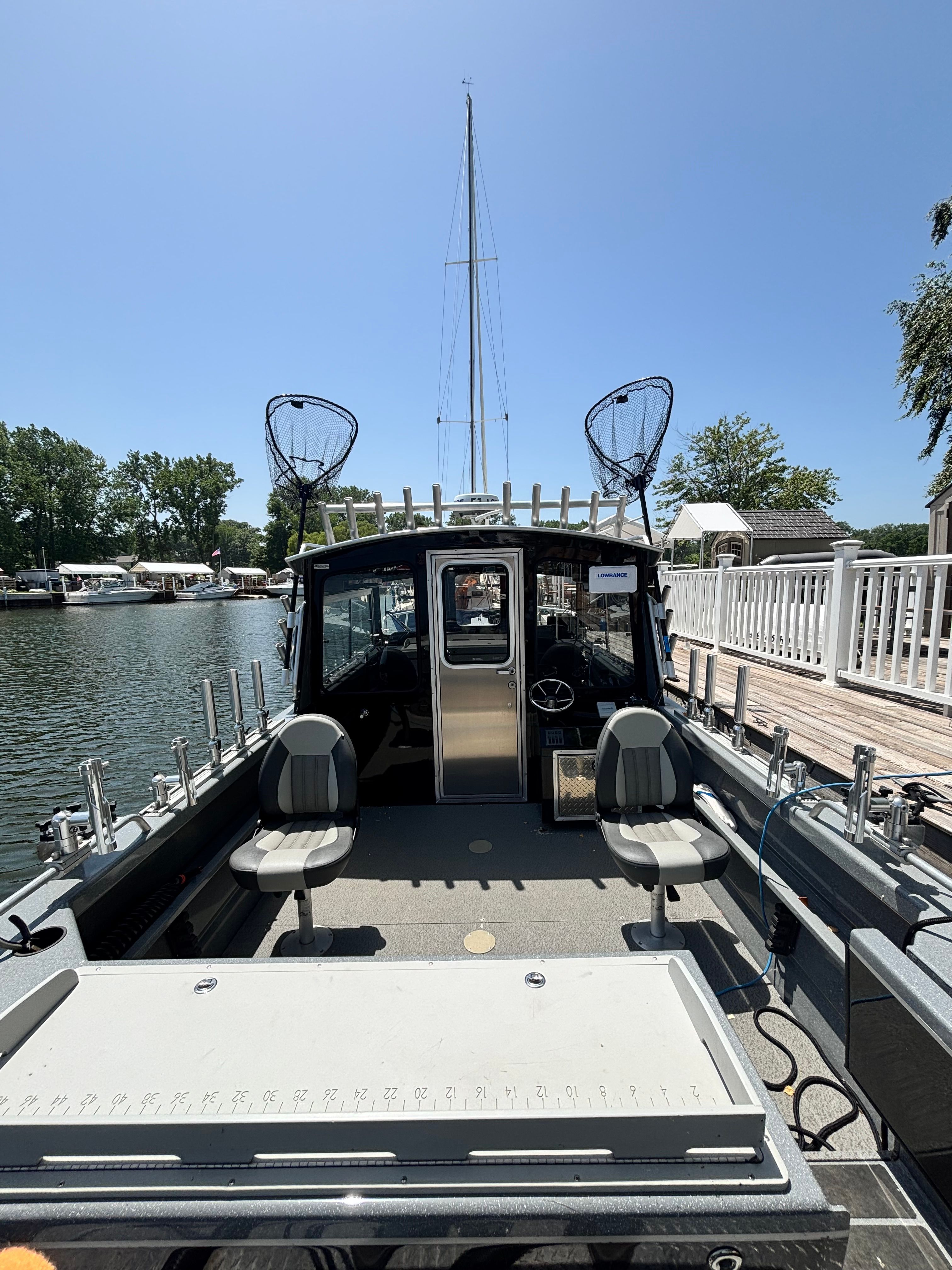 The image shows a boat with two seats and fishing rod holders, docked at a pier.