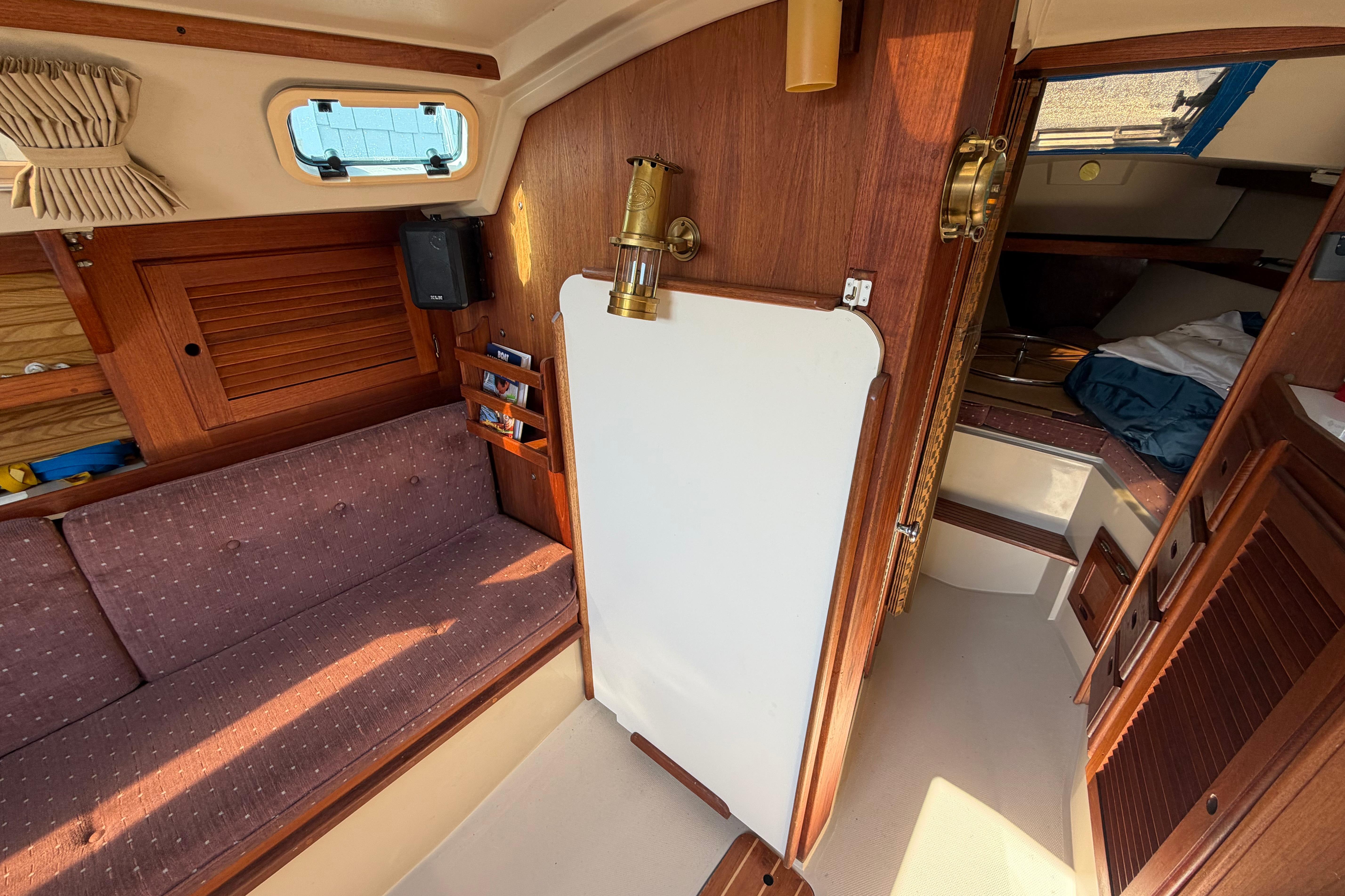 Interior of a 1988 Catalina 30 MkII sailboat, featuring cozy seating and wooden cabinetry.
