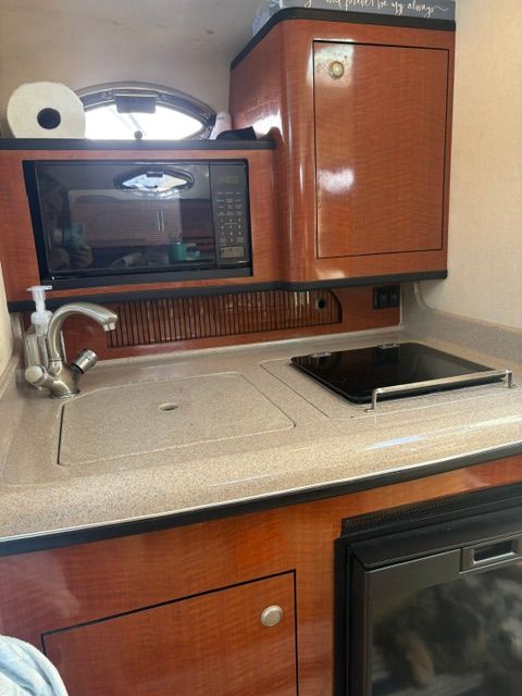 The galley of a 2005 Sea Ray Sundancer 280 with a sink, stove, and microwave.