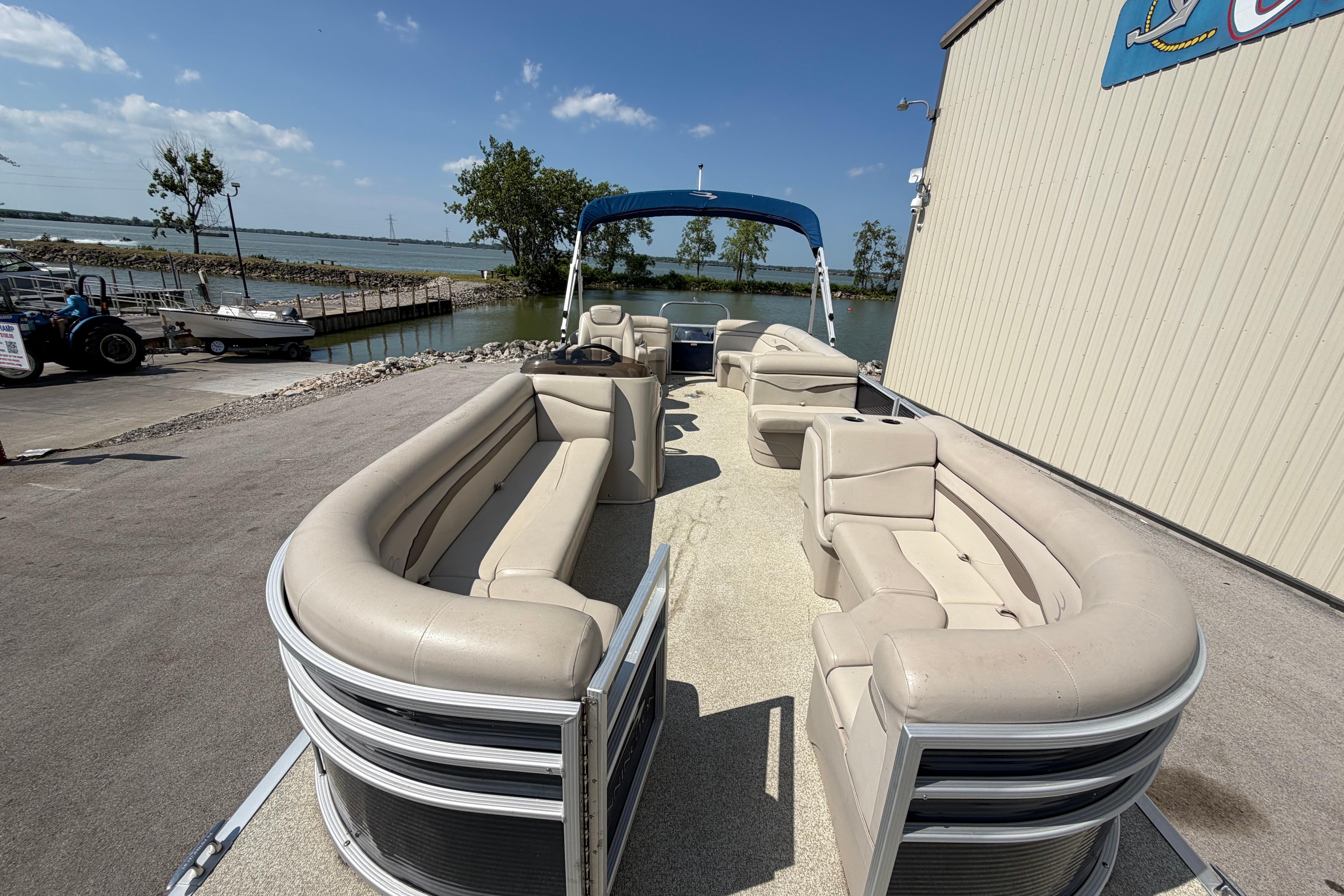 2017 Bennington 25 SSXAPG pontoon boat with beige seating, docked by a serene lake.