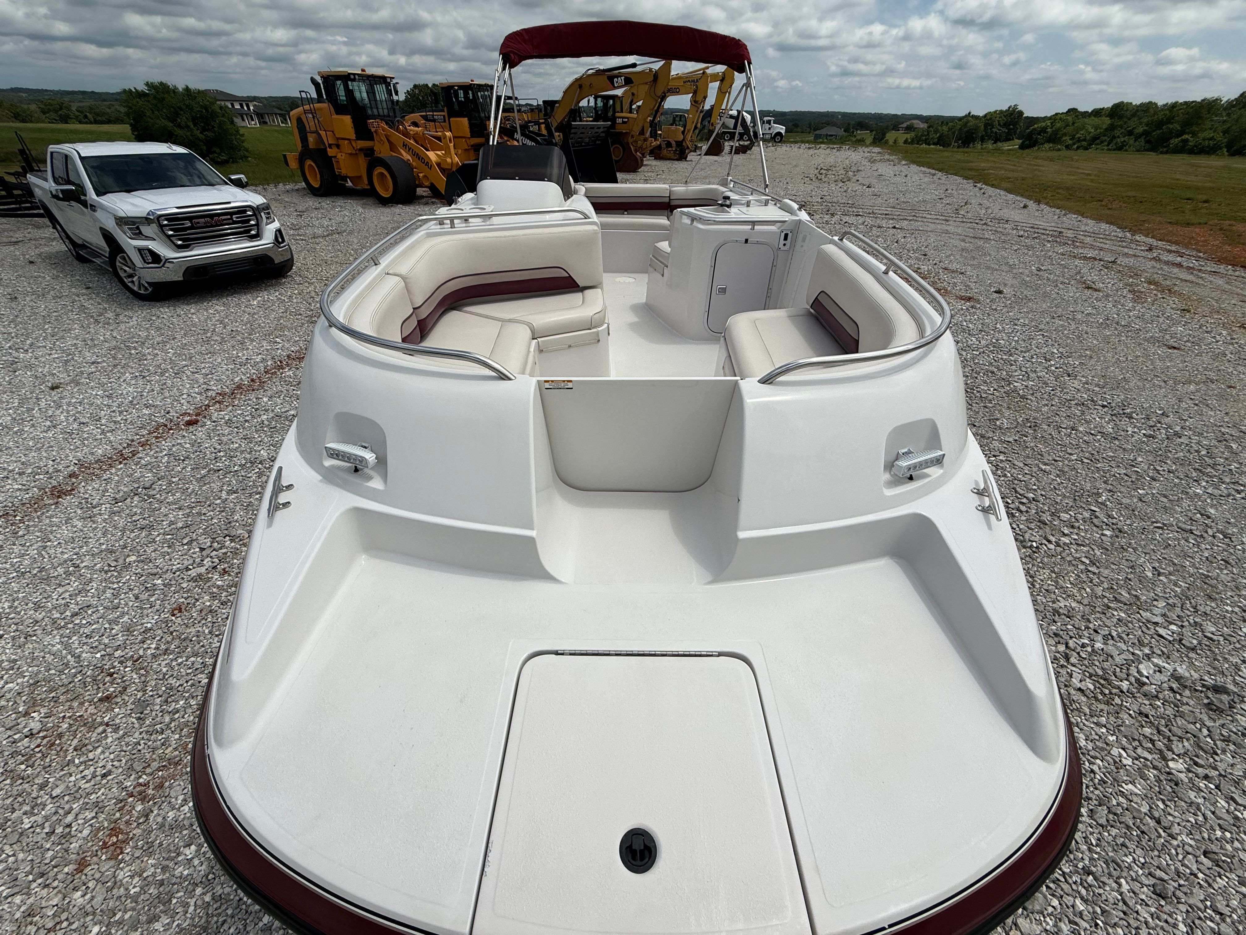 1994 Chaparral Sunesta 220 with spacious deck and red accents, parked on gravel.