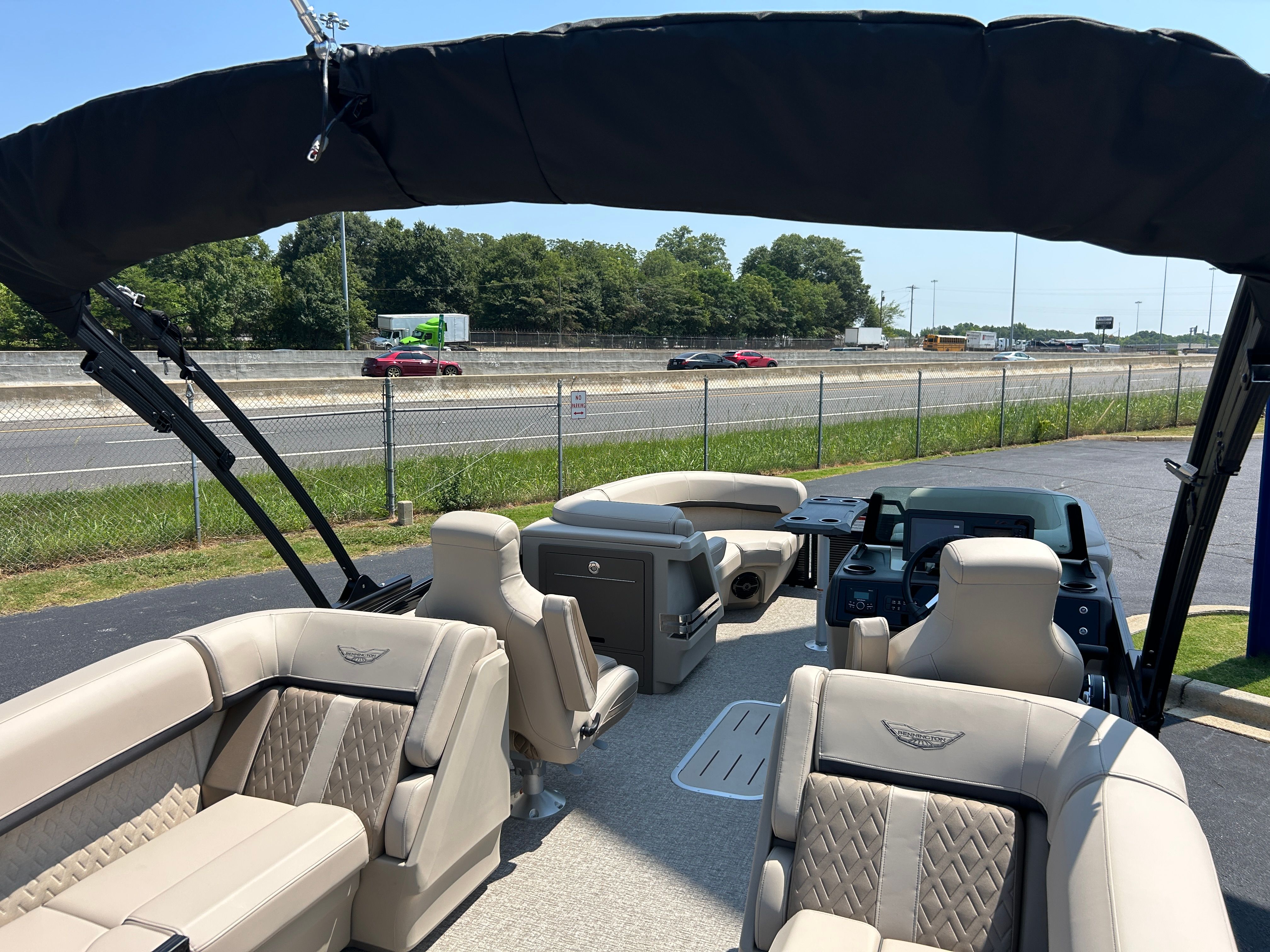 The image shows the interior of a Bennington 22 MFB boat with beige seating and a black canopy.