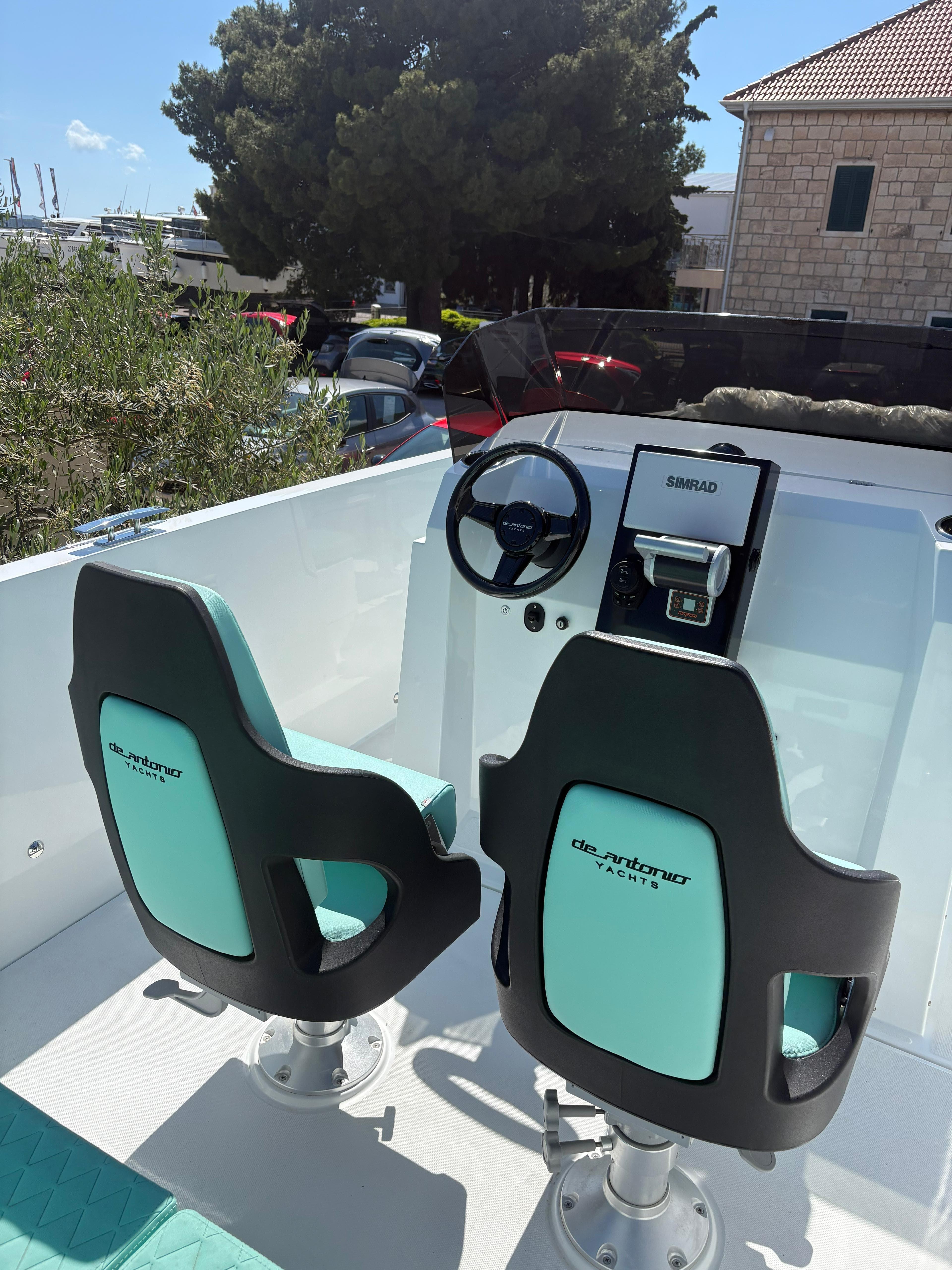 2025 De Antonio Yachts e23 Open cockpit with dual teal seats and steering console.