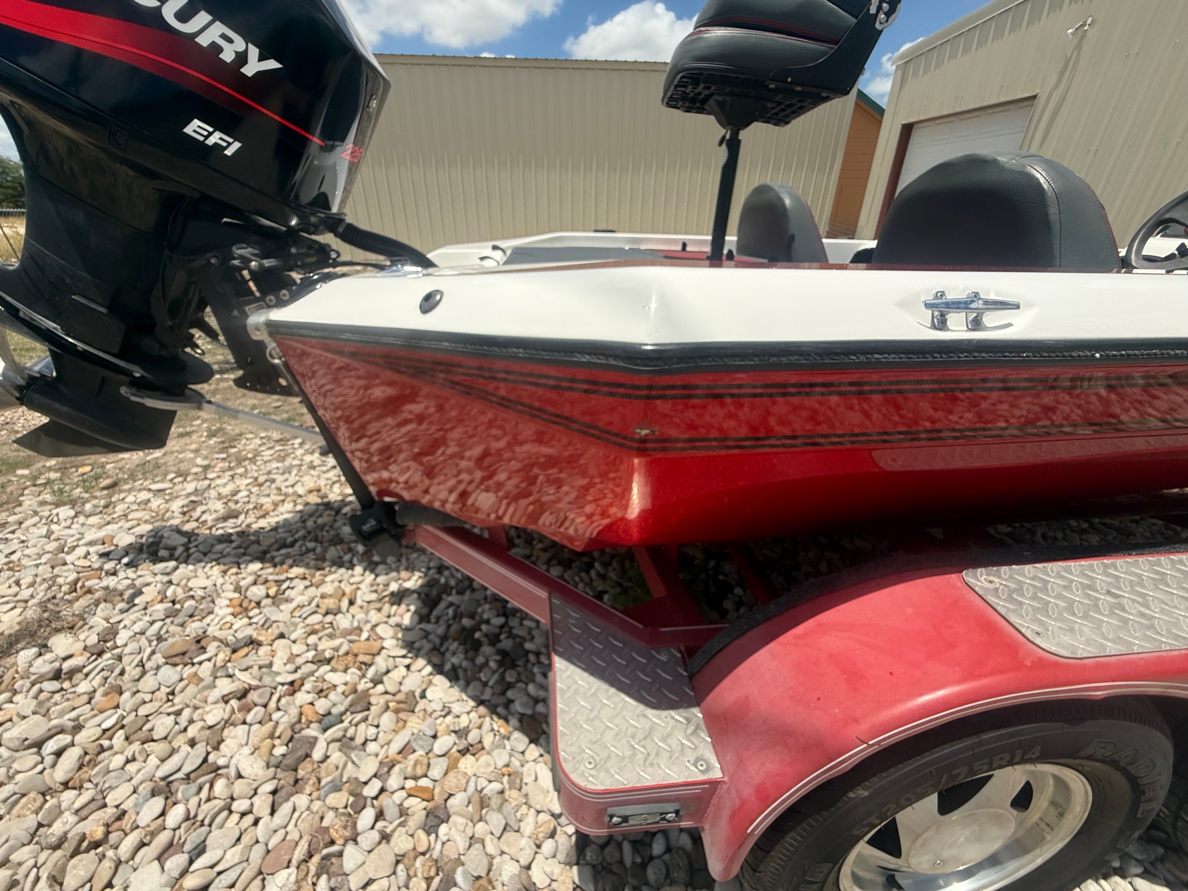 A red 1999 Champion 202 boat with a Mercury EFI engine, on a trailer.