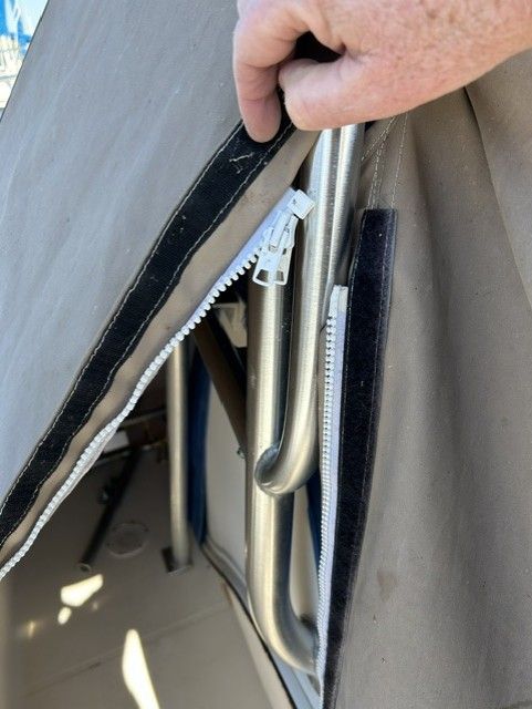 Close-up of a zipper on a boat with gray fabric and metal frame.
