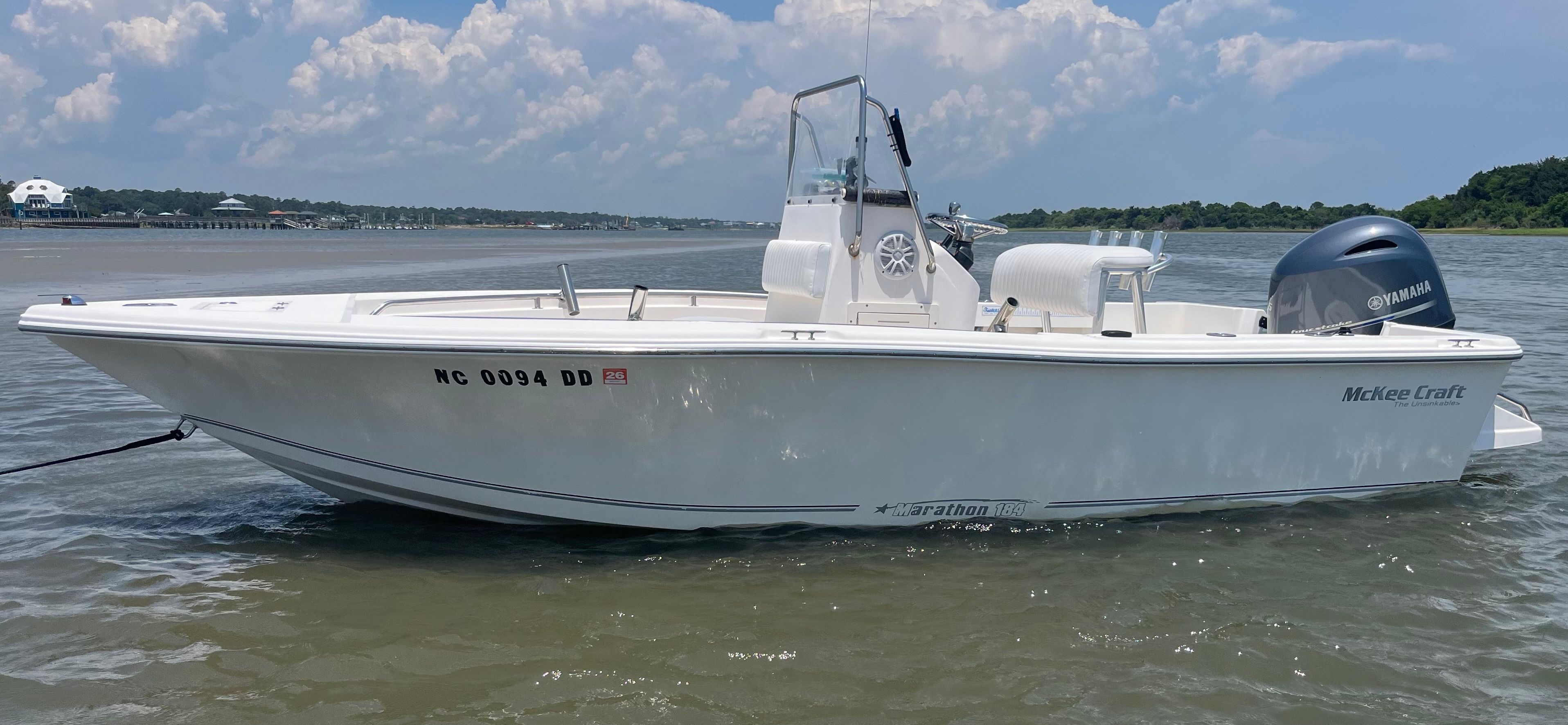 A white McKee Craft boat on calm water with a blue sky in the background.