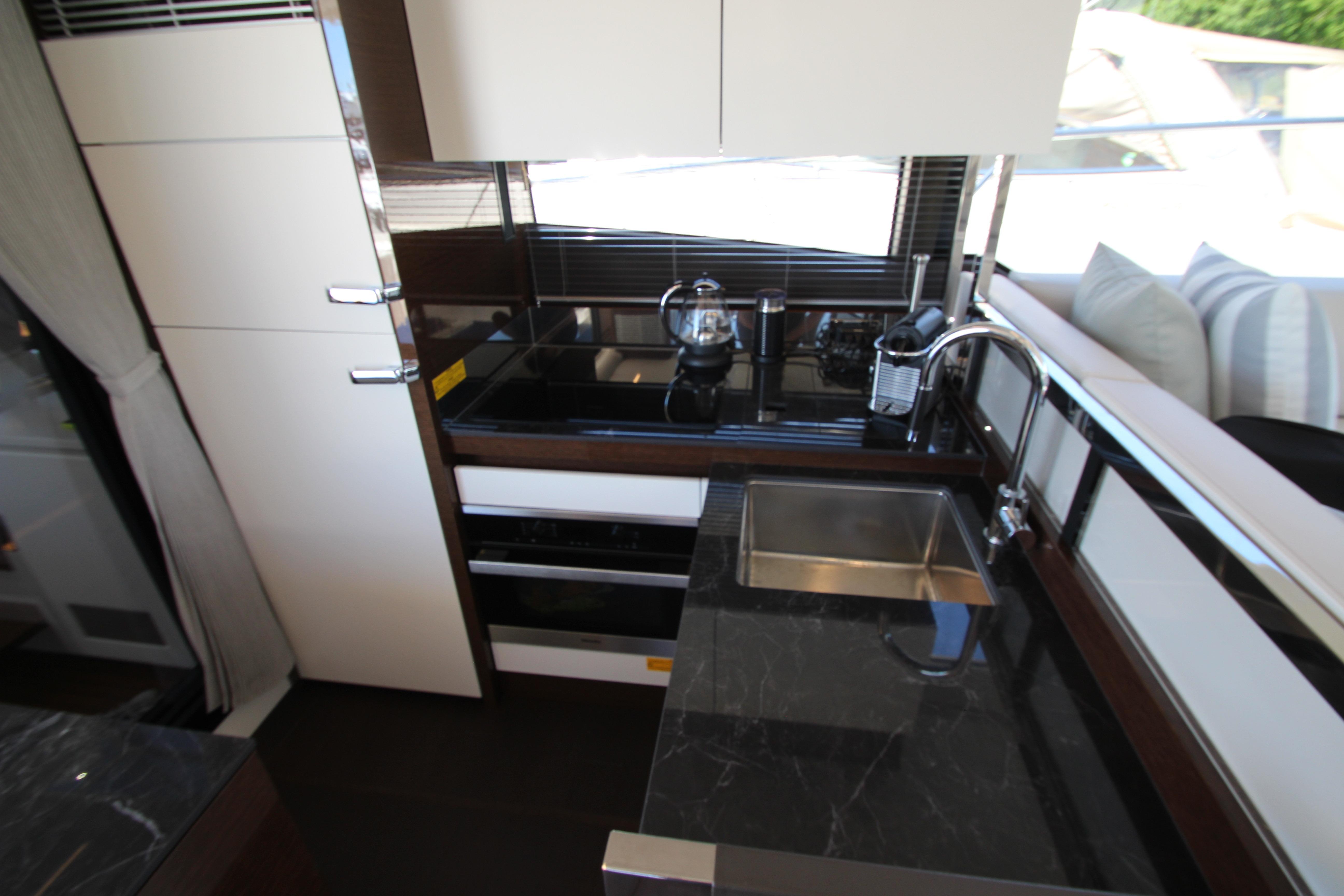 Modern kitchen interior on 2022 Prestige 520 yacht, featuring sleek countertops and stainless steel sink.