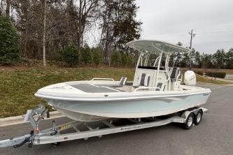 2025 Ranger 2360 Bay boat on trailer, parked outdoors, surrounded by trees.