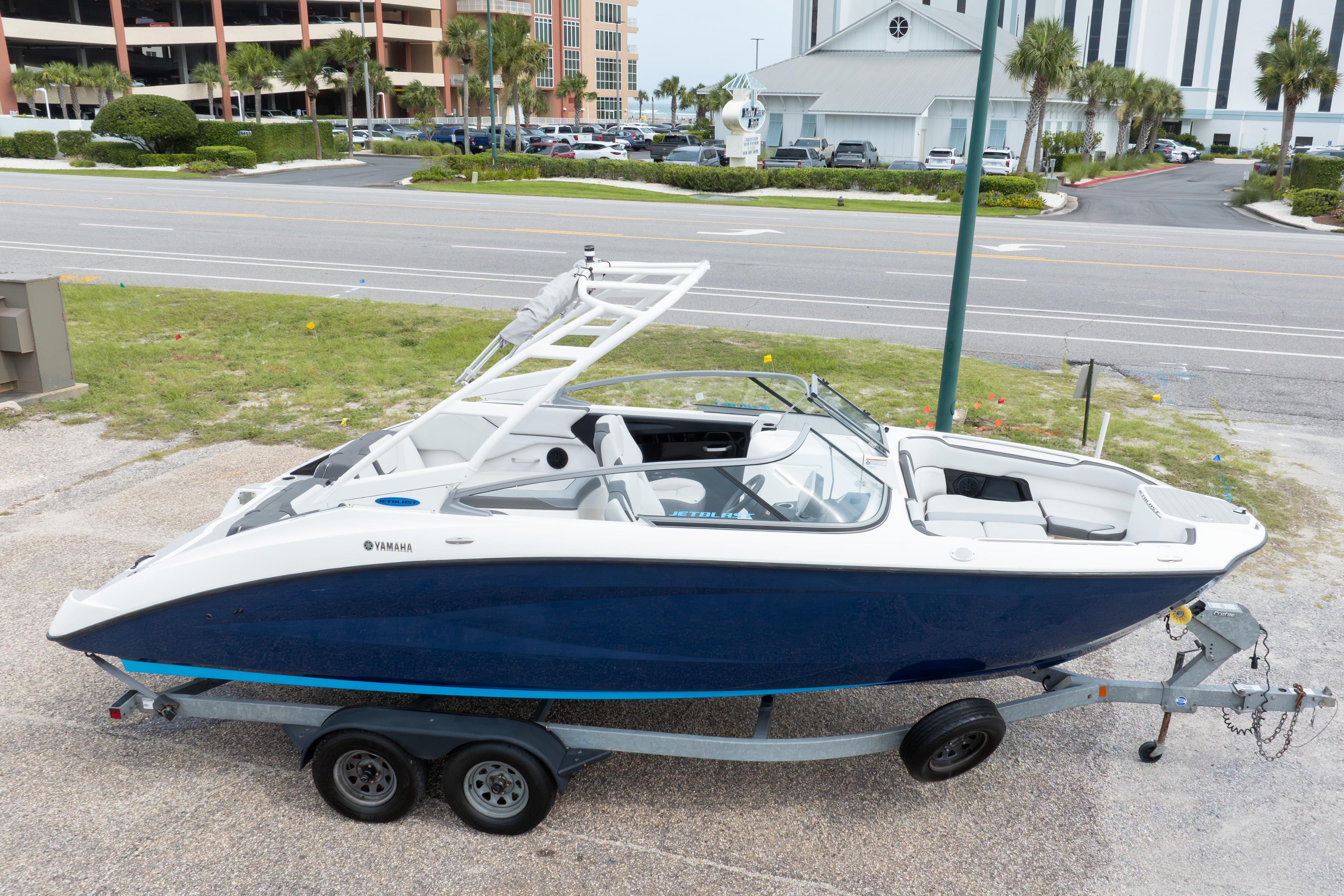 2021 Yamaha Boats AR250 on trailer, parked near a road with buildings in the background.