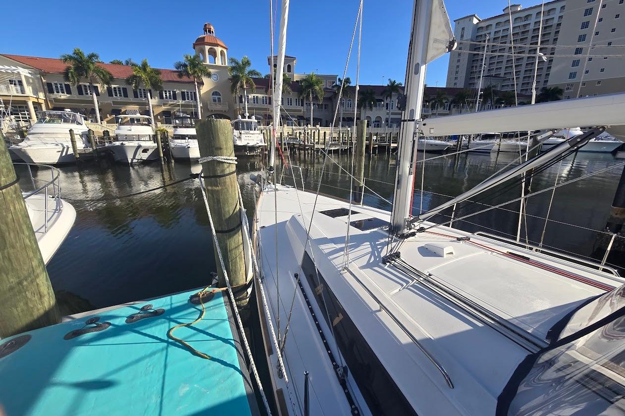 2023 Beneteau Oceanis 38.1 yacht docked at a marina with waterfront buildings.