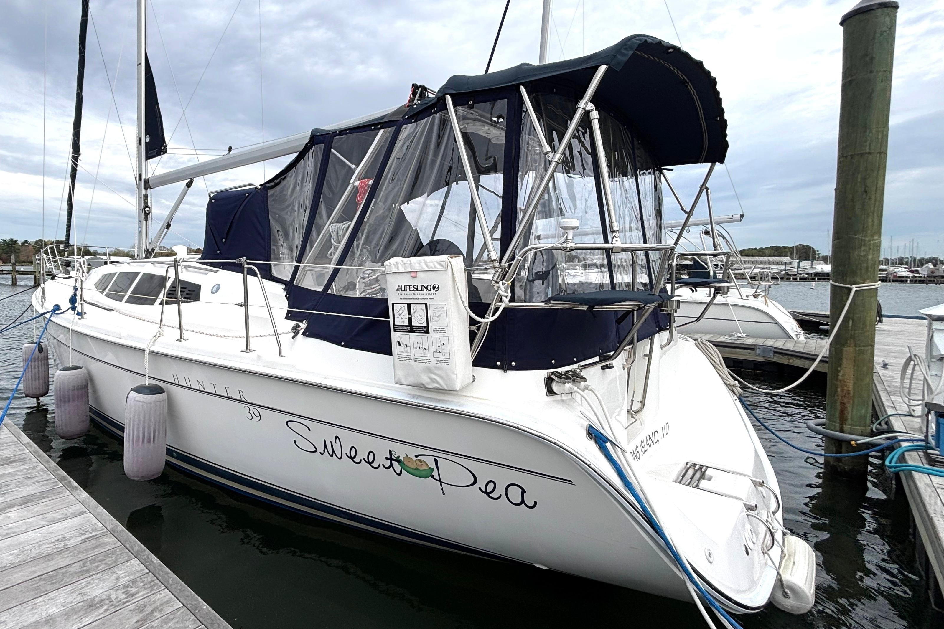 2011 Hunter 39 sailboat docked, featuring a navy canopy and "Sweet Pea" name on the stern.