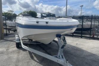 2022 Hurricane SunDeck 192 OB boat on trailer, parked outdoors under cloudy sky.