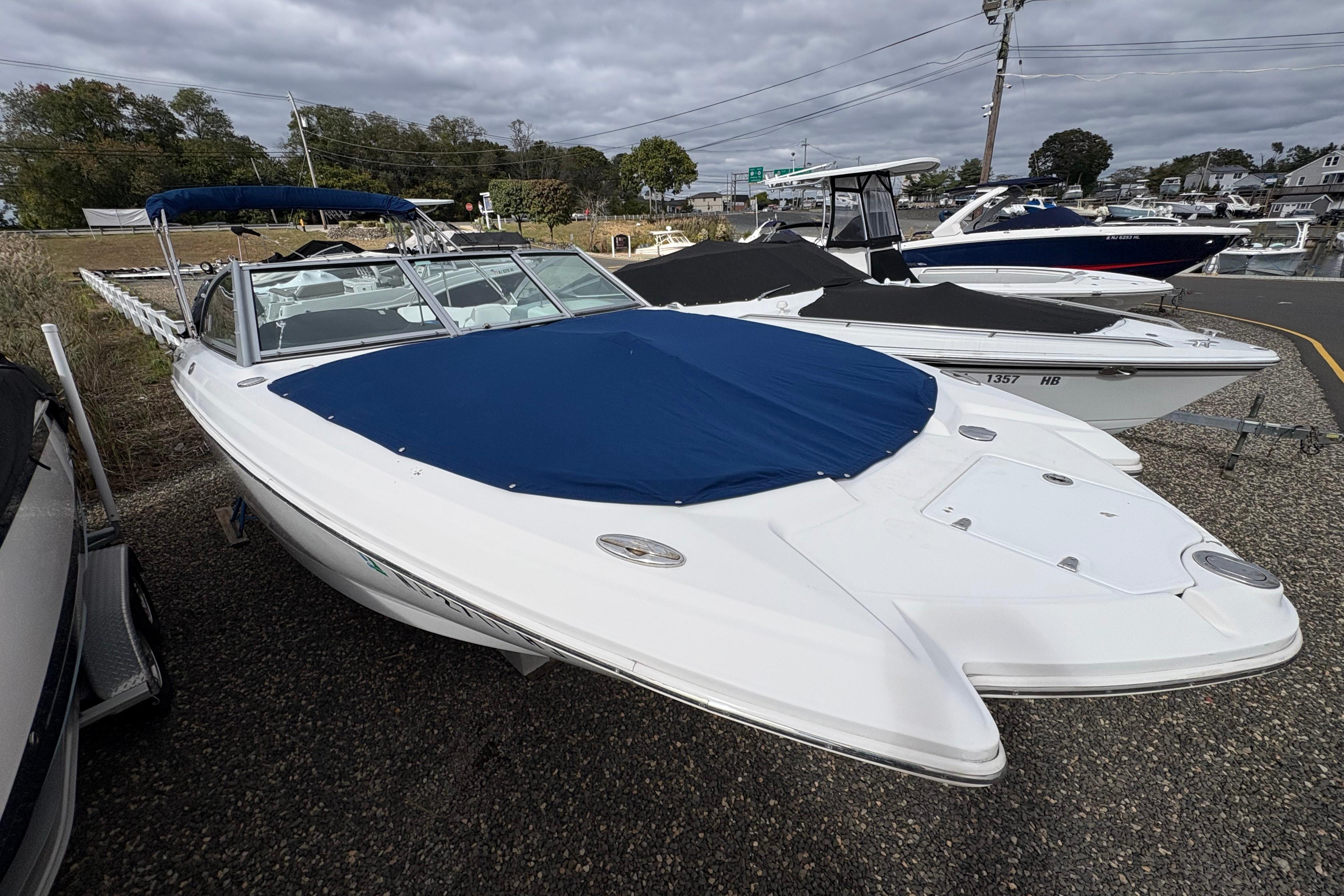 2015 Chaparral 264 Sunesta boat with blue cover, parked outdoors.
