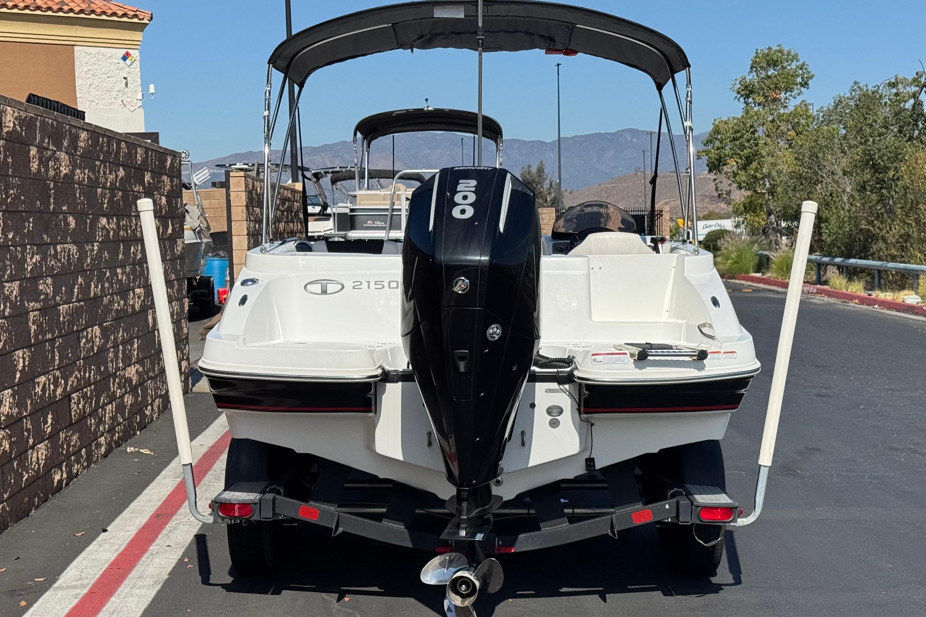 2019 Tahoe 2150 boat with outboard motor on trailer, parked near a wall.