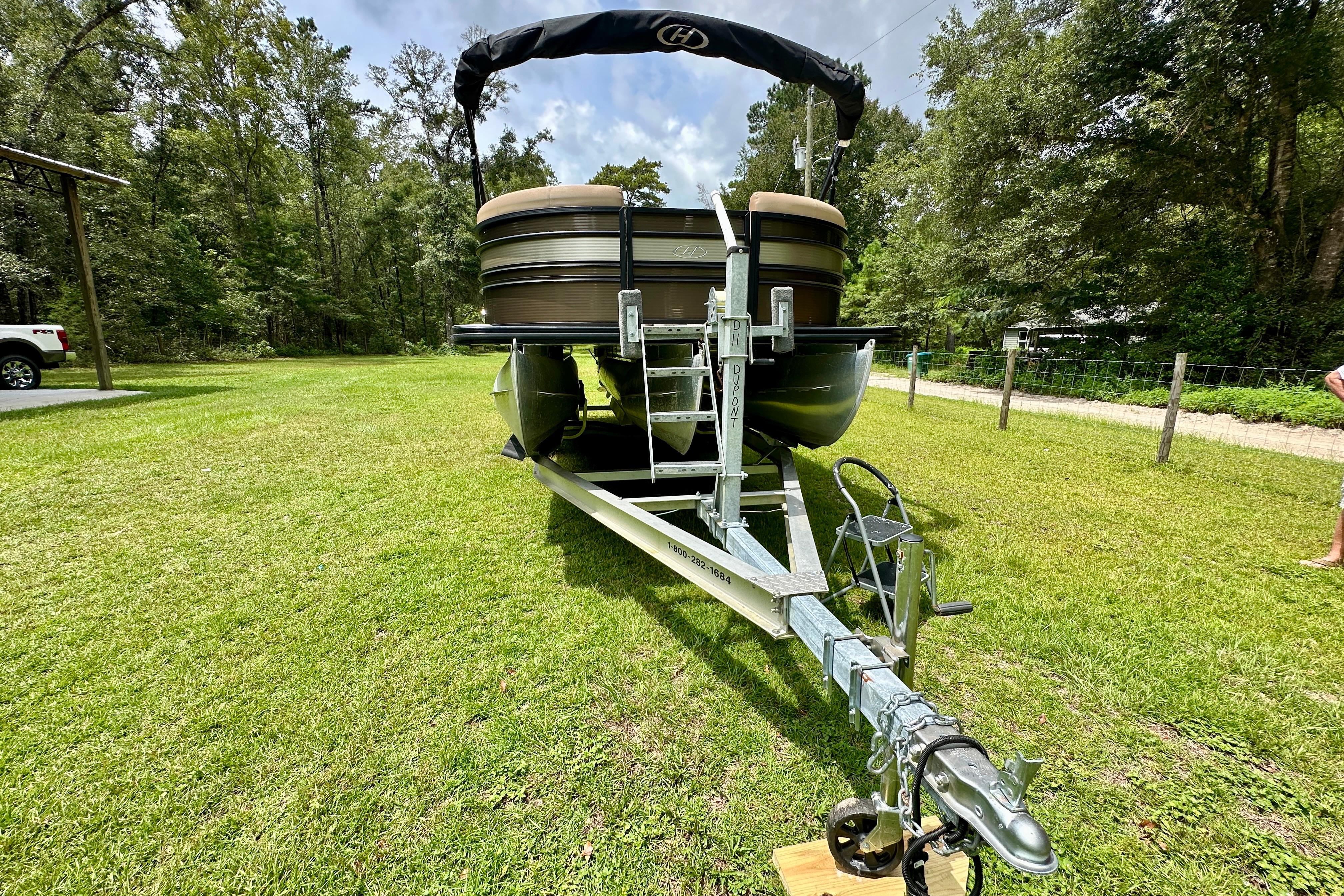 2022 Harris FloteBote 230 Super Sunliner LX on trailer, parked on grassy area.