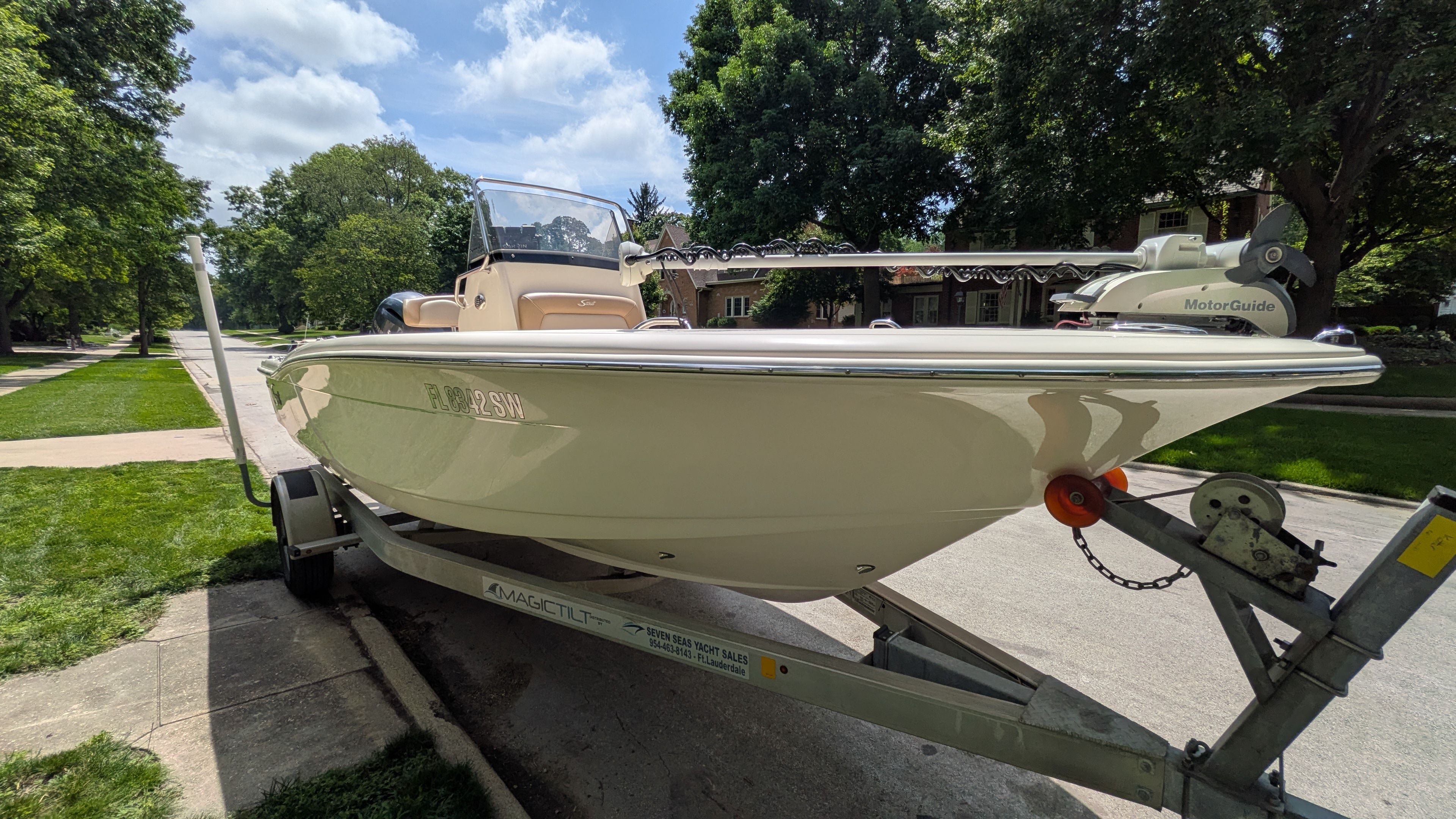 A 2021 Scout 195 Sportfish boat on a trailer in a residential street.