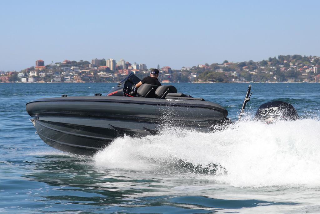 2019 Ribco R28s speedboat cruising on open water with cityscape in background.