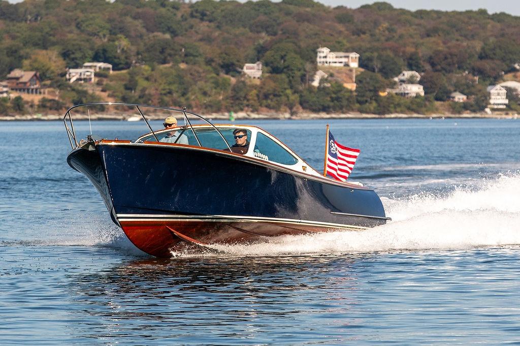 2003 Hinckley T29R boat cruising on a scenic lake with American flag.
