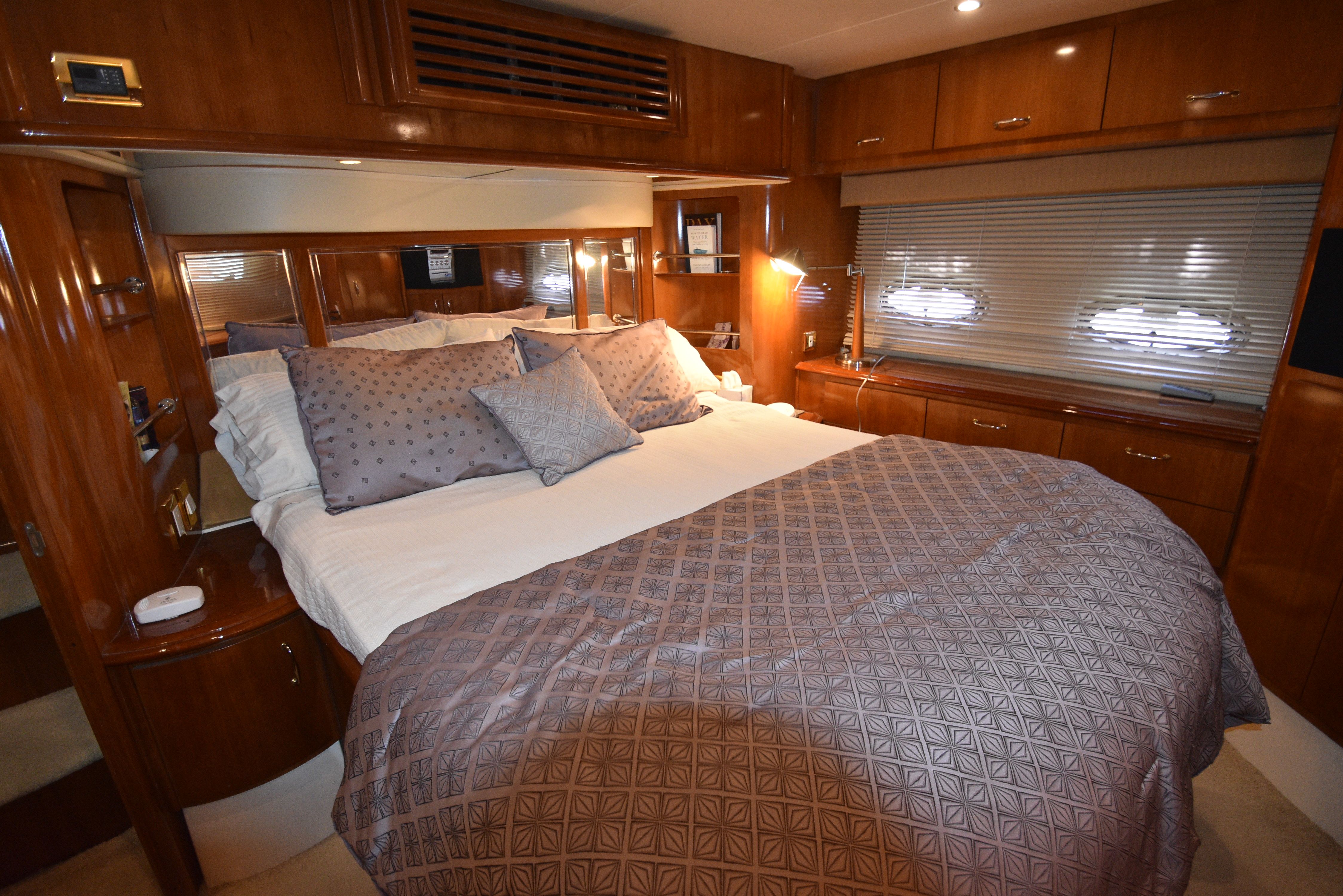 Luxurious bedroom with a large bed, wooden furnishings, and plush pillows on a yacht.