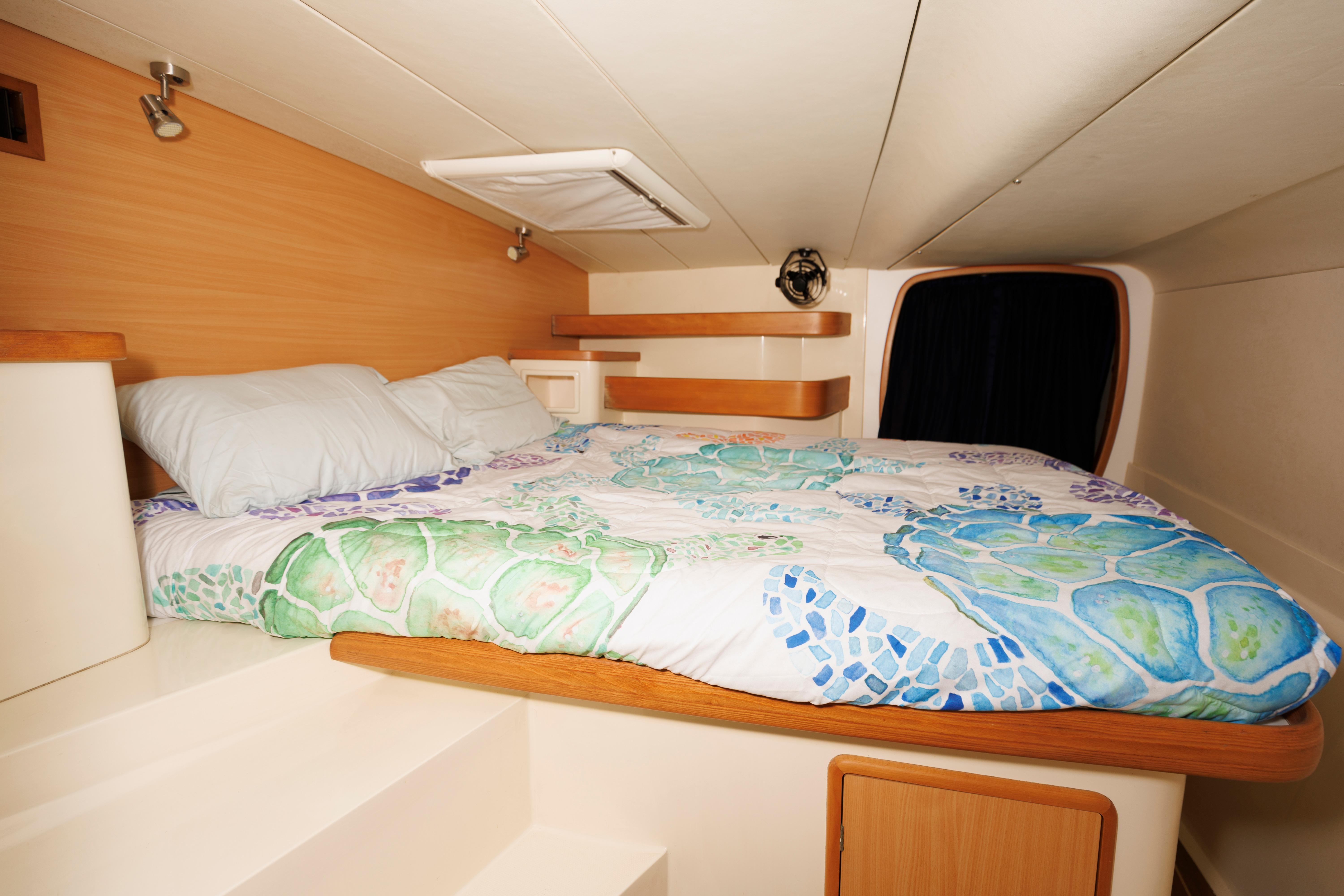 Cozy cabin interior of 2006 Leopard 43 yacht with colorful bedding and wooden accents.