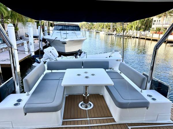 Aquila 44 yacht interior with seating and table, docked by a serene waterfront.