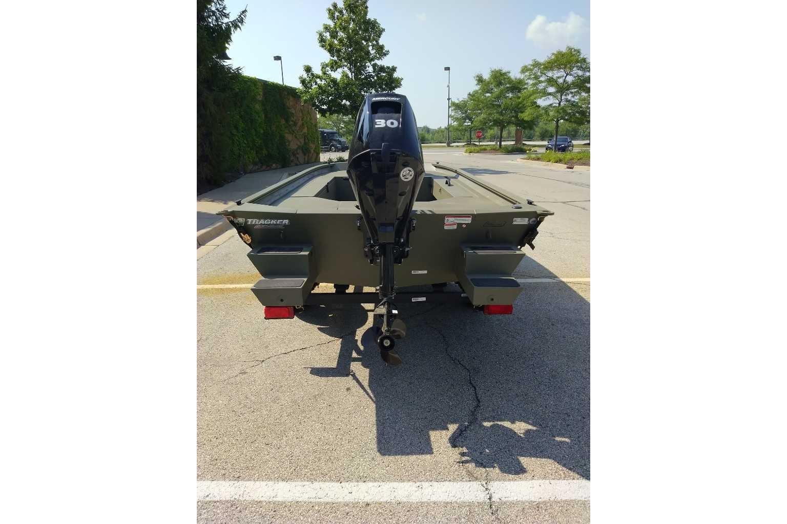 2026 Tracker Grizzly 1654 T Sportsman boat, rear view with motor, parked outdoors.