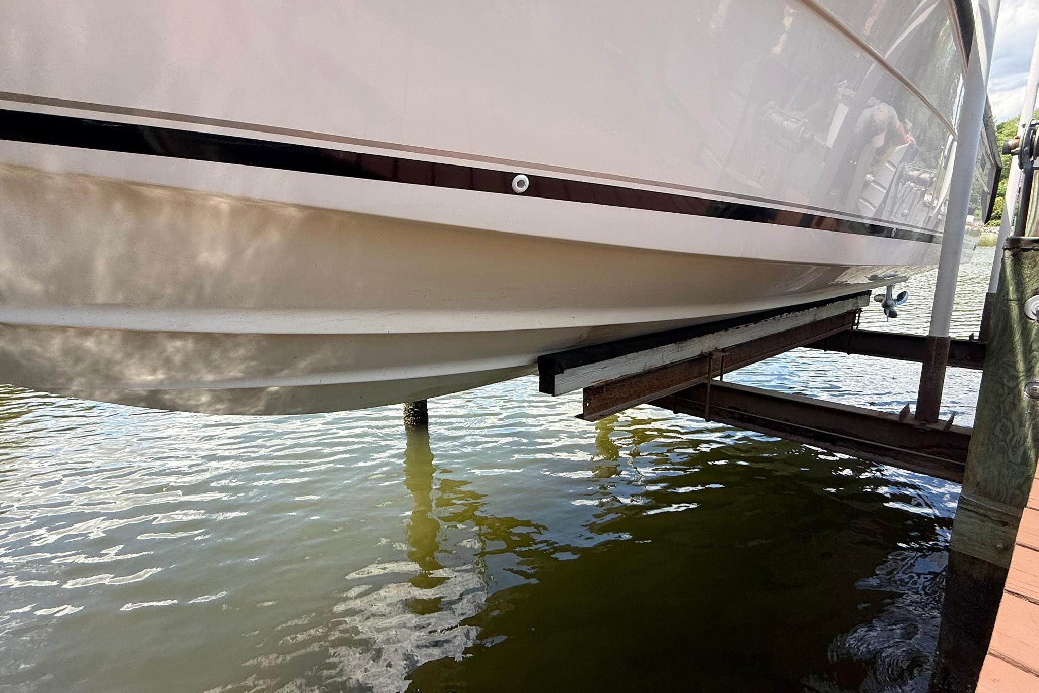 2003 Pursuit 2870 Walkaround boat hull on lift above water.