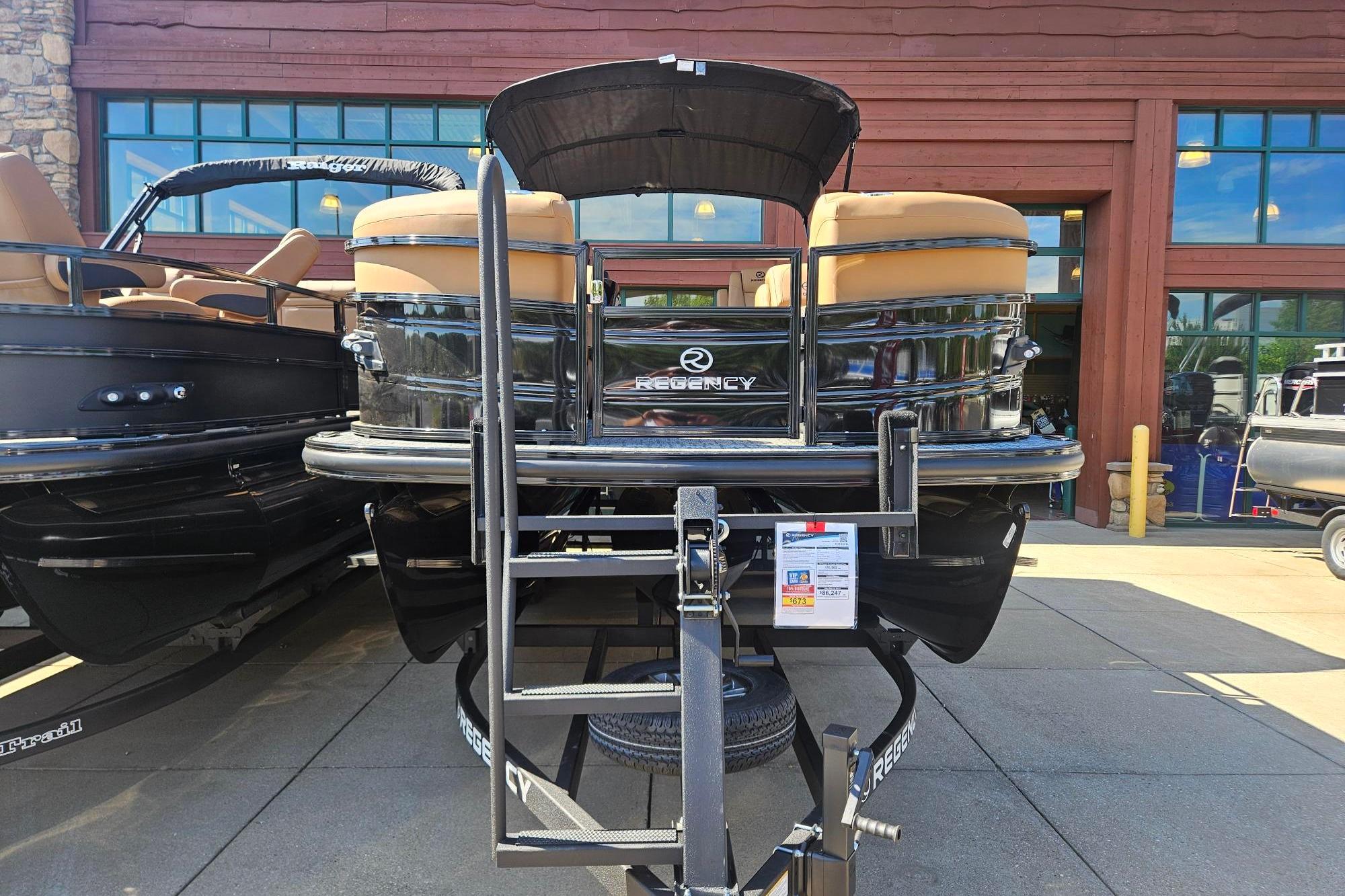 2026 Regency 230 DL pontoon boat displayed on a trailer outside a showroom.