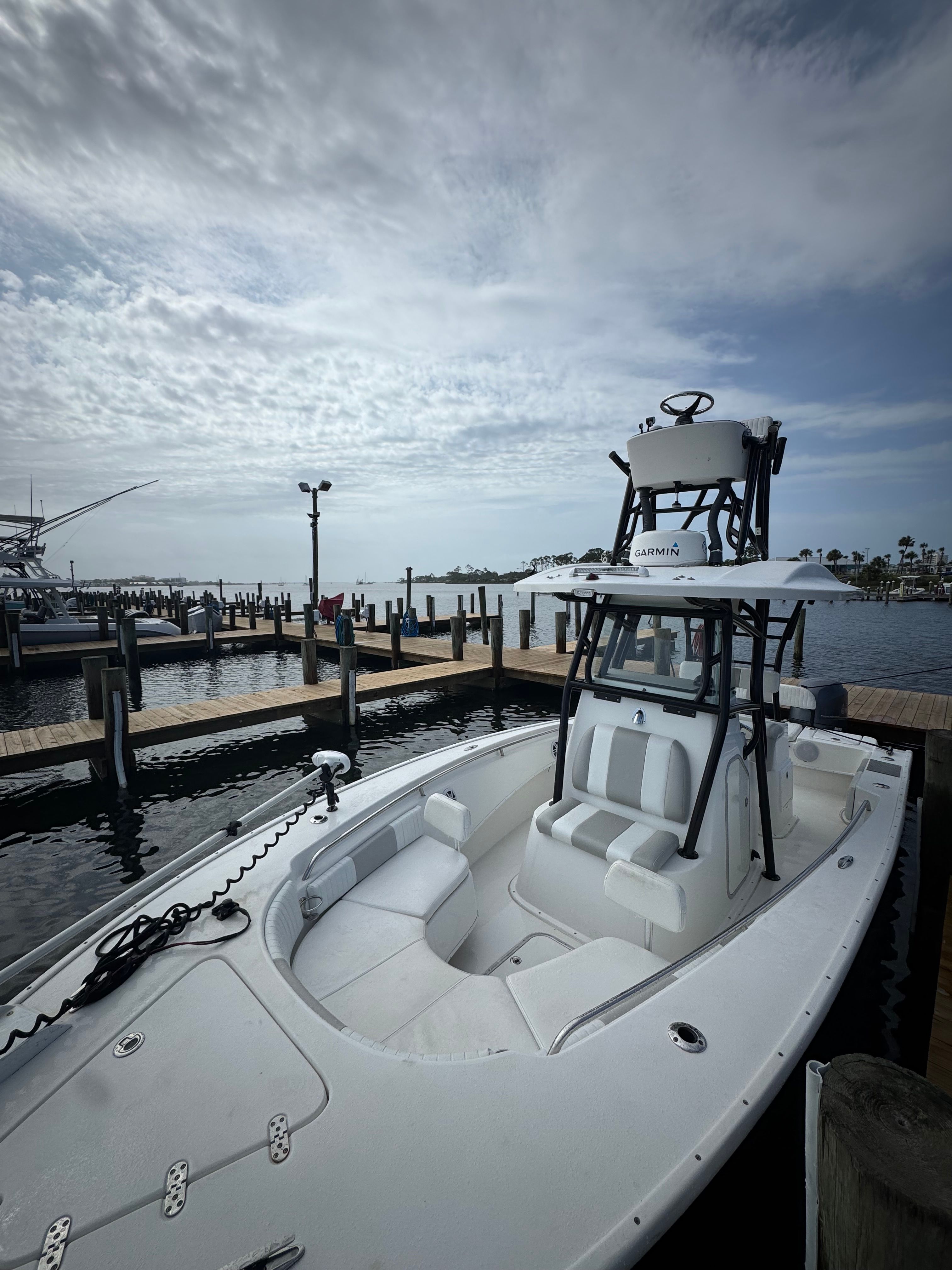 A white boat is docked with an elevated helm station.