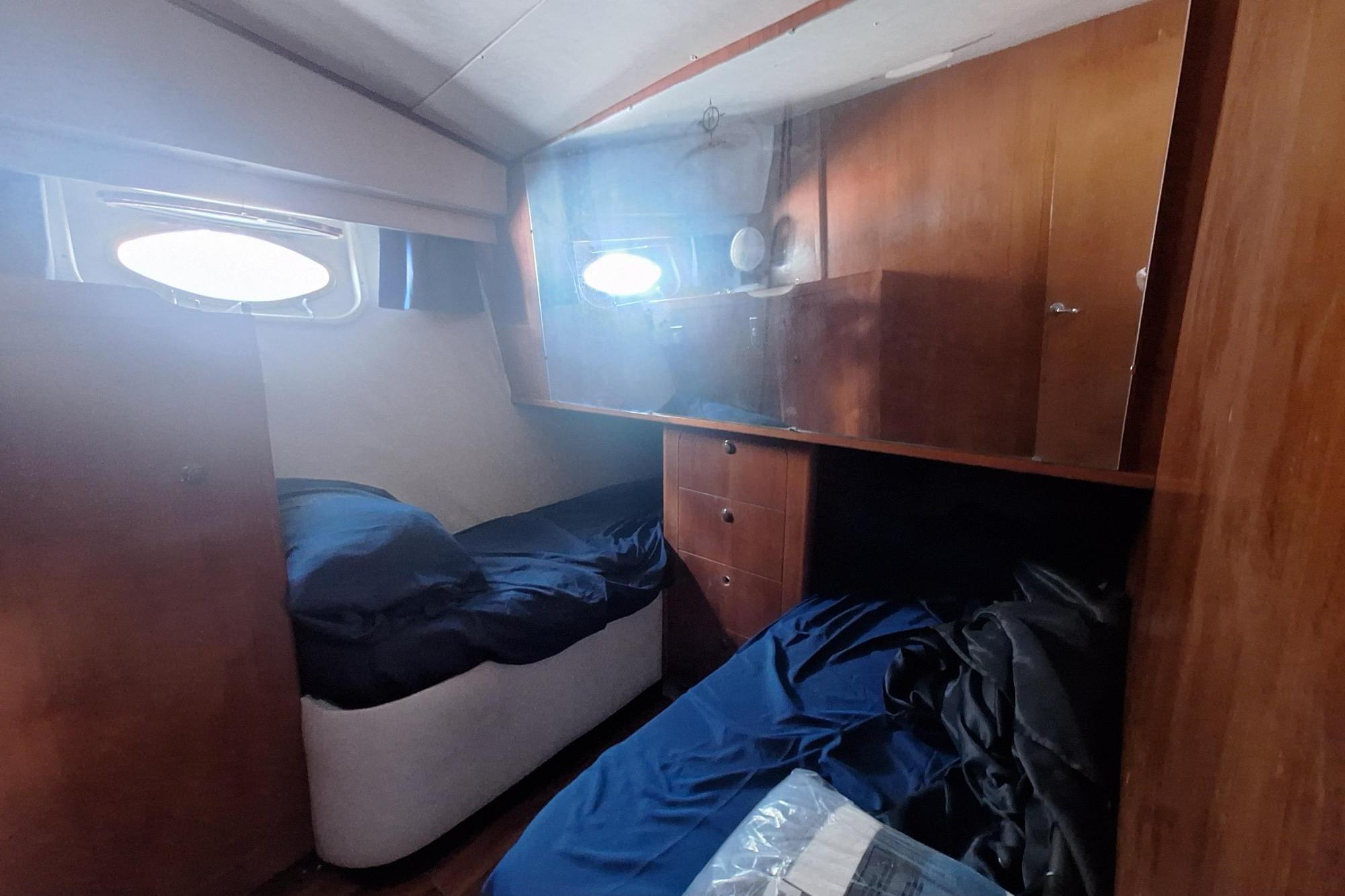 Cozy cabin interior of 1988 Birchwood 44TS yacht with wooden furnishings and twin beds.