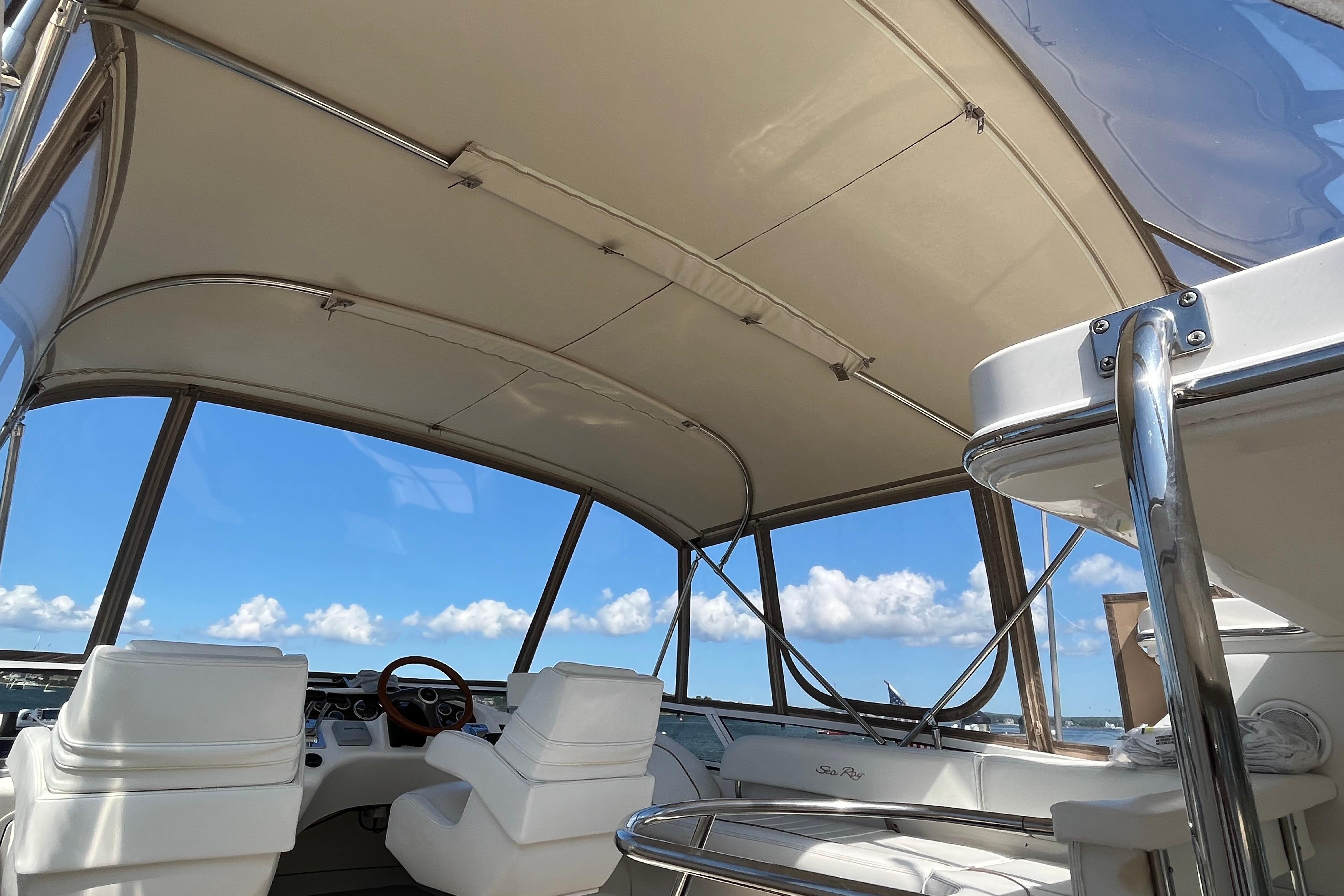 1997 Sea Ray 420 Aft Cabin interior with helm, white seating, and clear blue sky.