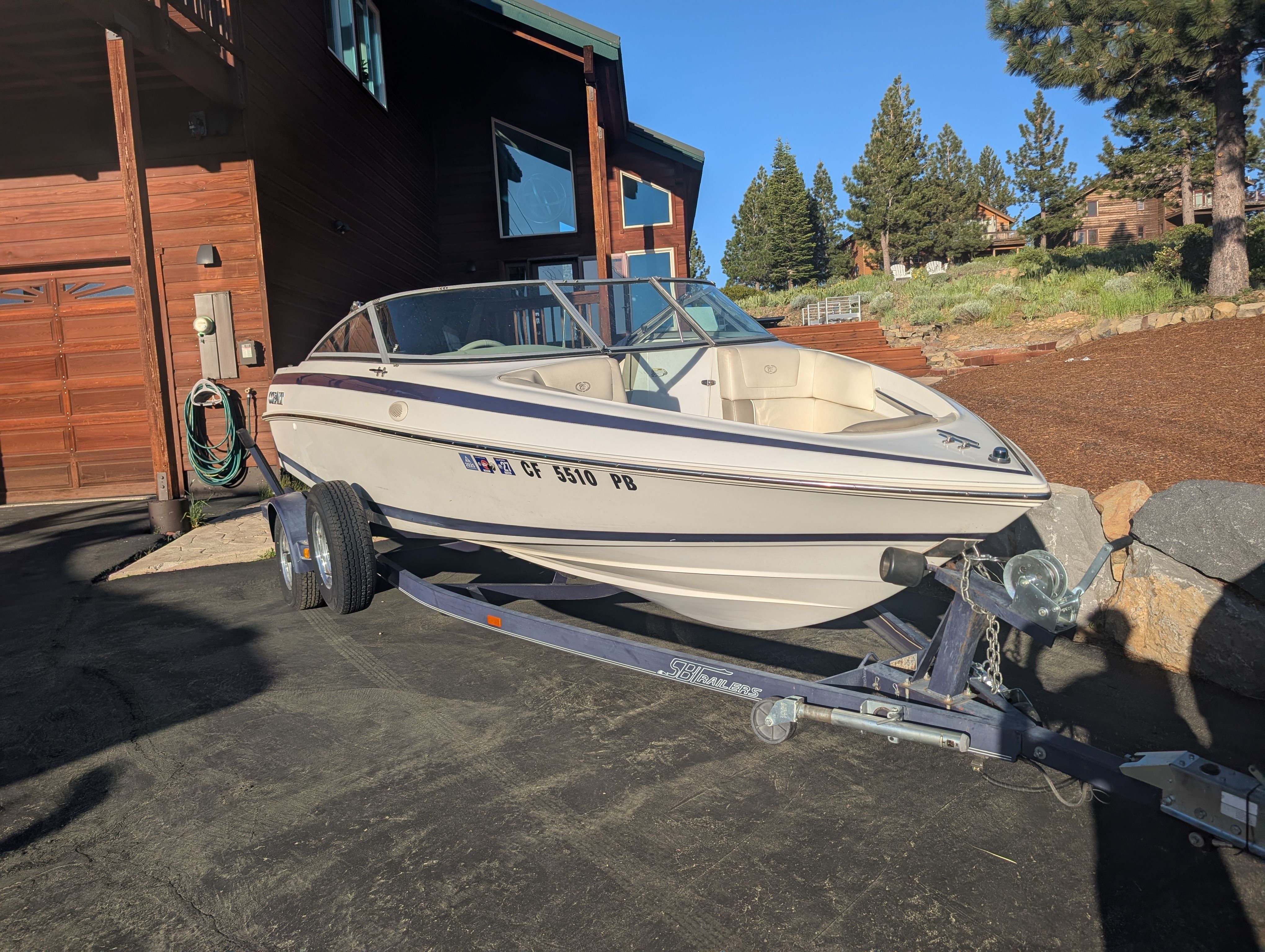 A 1997 Cobalt 190 boat on a trailer beside a house.