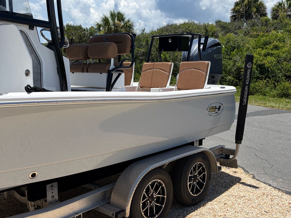 A Sea Hunt BX 22 BR boat on a trailer, surrounded by trees and sky.