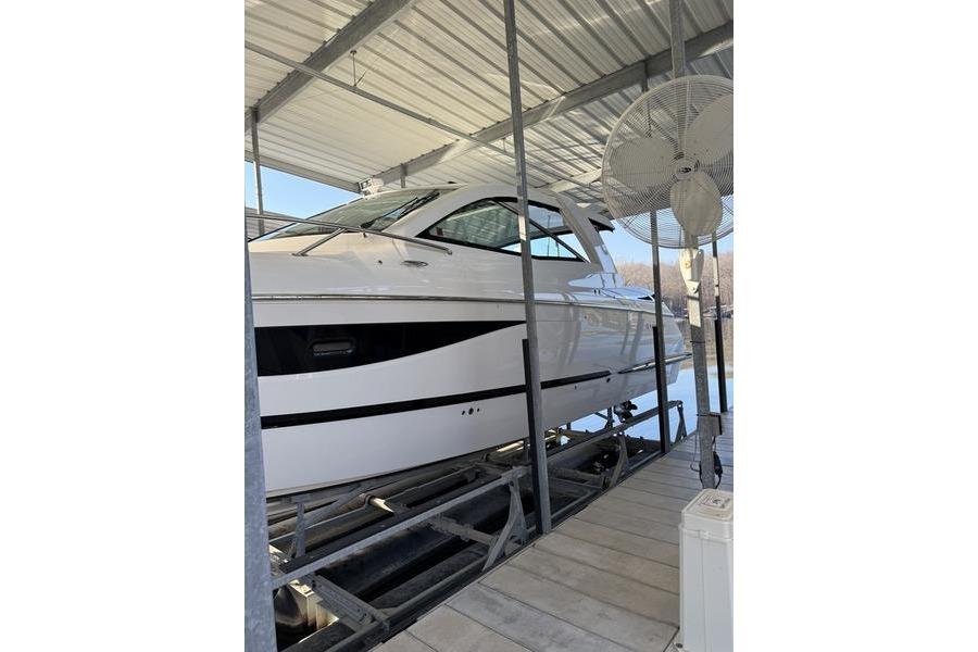 2016 Cobalt A40 boat in covered dock, side view with fan and railing.