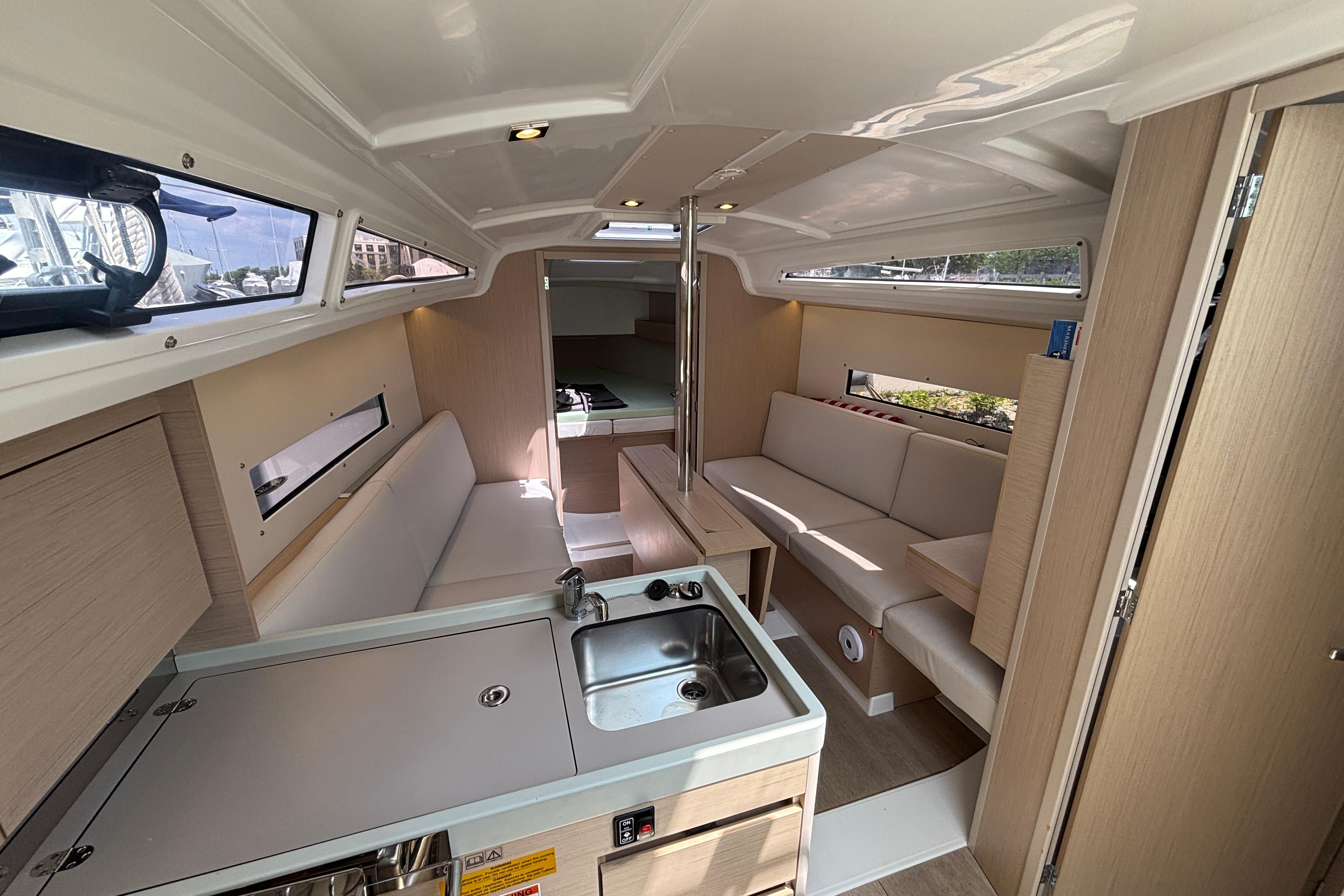 Interior of 2021 Beneteau Oceanis 30.1 yacht, featuring modern seating and compact kitchen area.