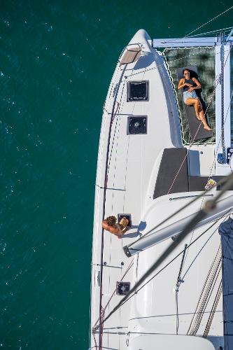 Aerial view of Lagoon 43 yacht, 2025 model, with people relaxing on deck over turquoise water.