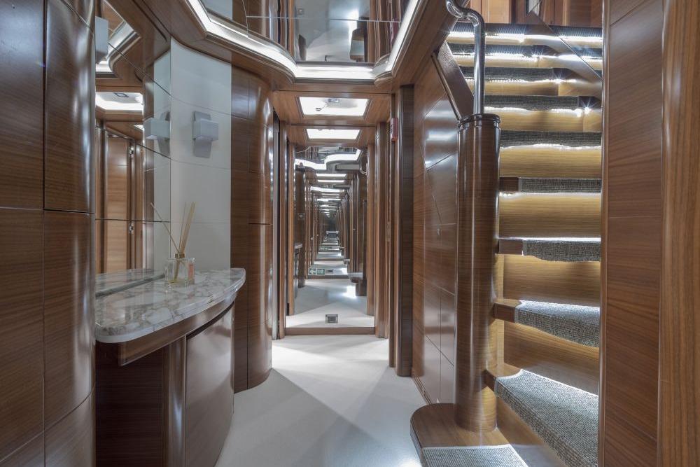 Luxurious interior of 2009 CRN 129 yacht with elegant wood paneling and illuminated staircase.