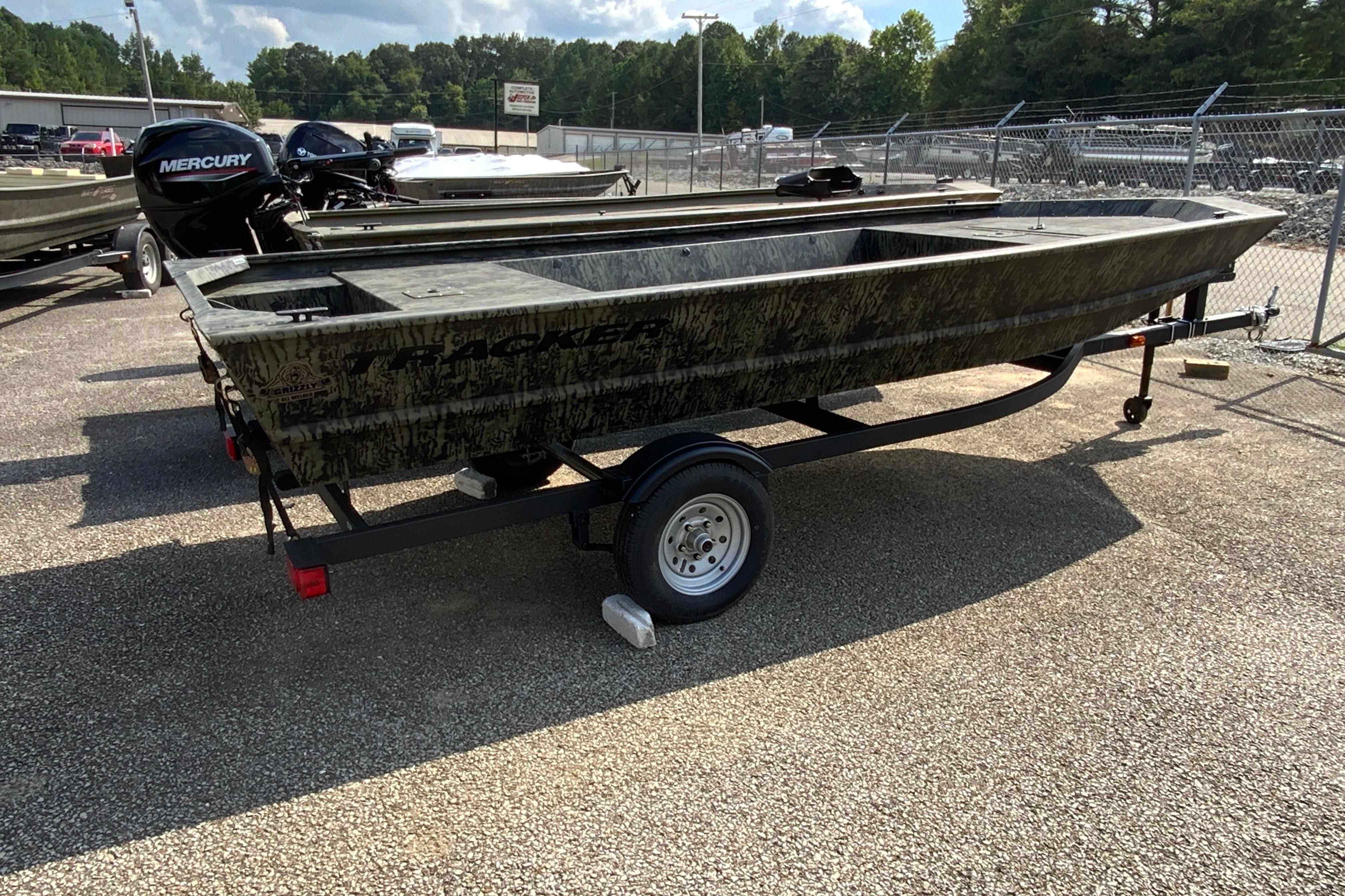 2026 Tracker Grizzly 1648 Utility boat on trailer, parked outdoors, with Mercury outboard motor.