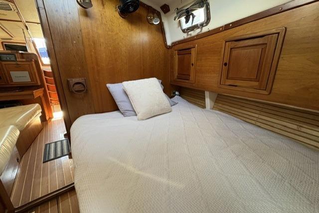 Cozy cabin interior of 2002 Saga 43 sailboat with wooden finish and comfortable bedding.