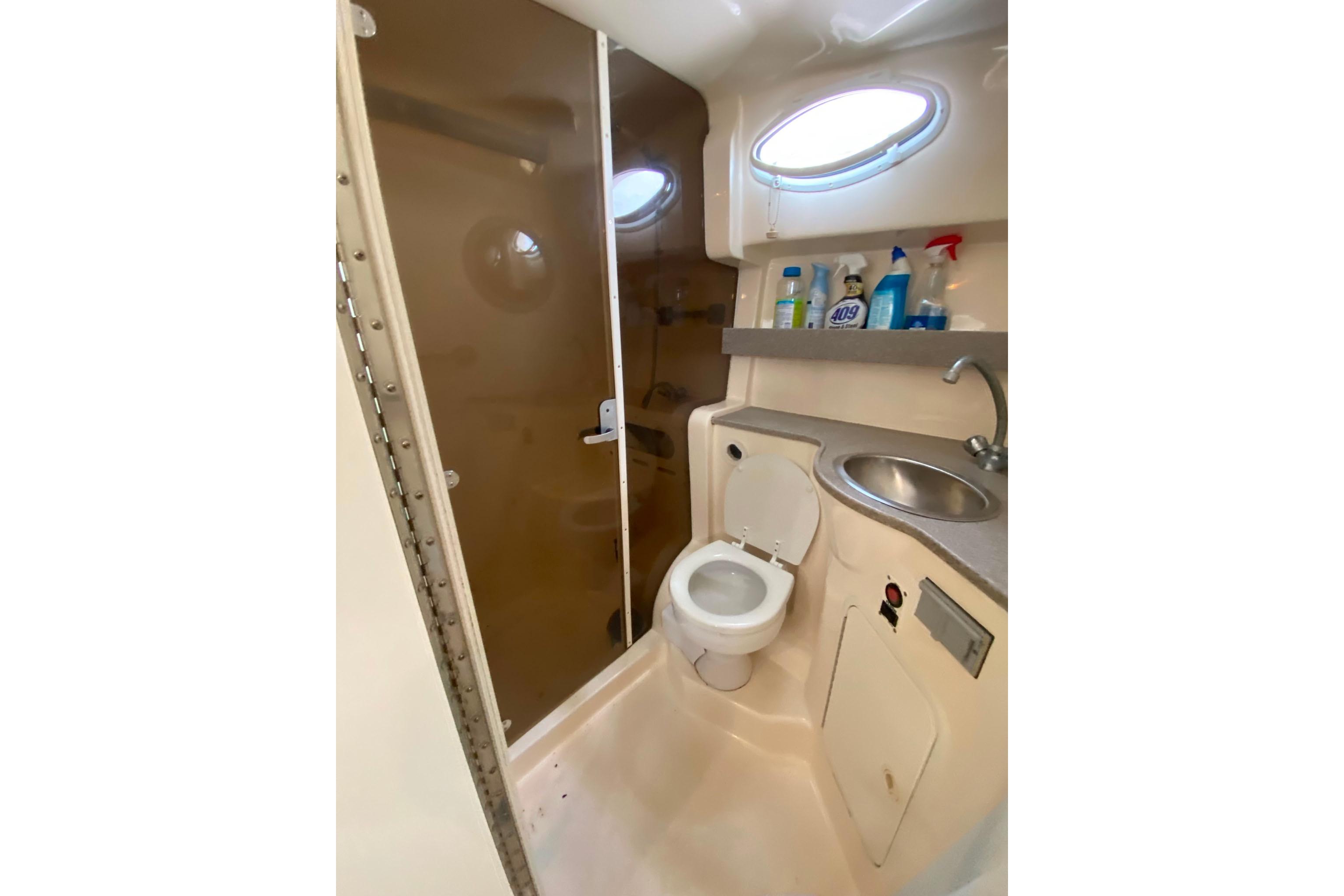 2003 Rinker Fiesta Vee 342 bathroom with shower, toilet, sink, and cleaning supplies.