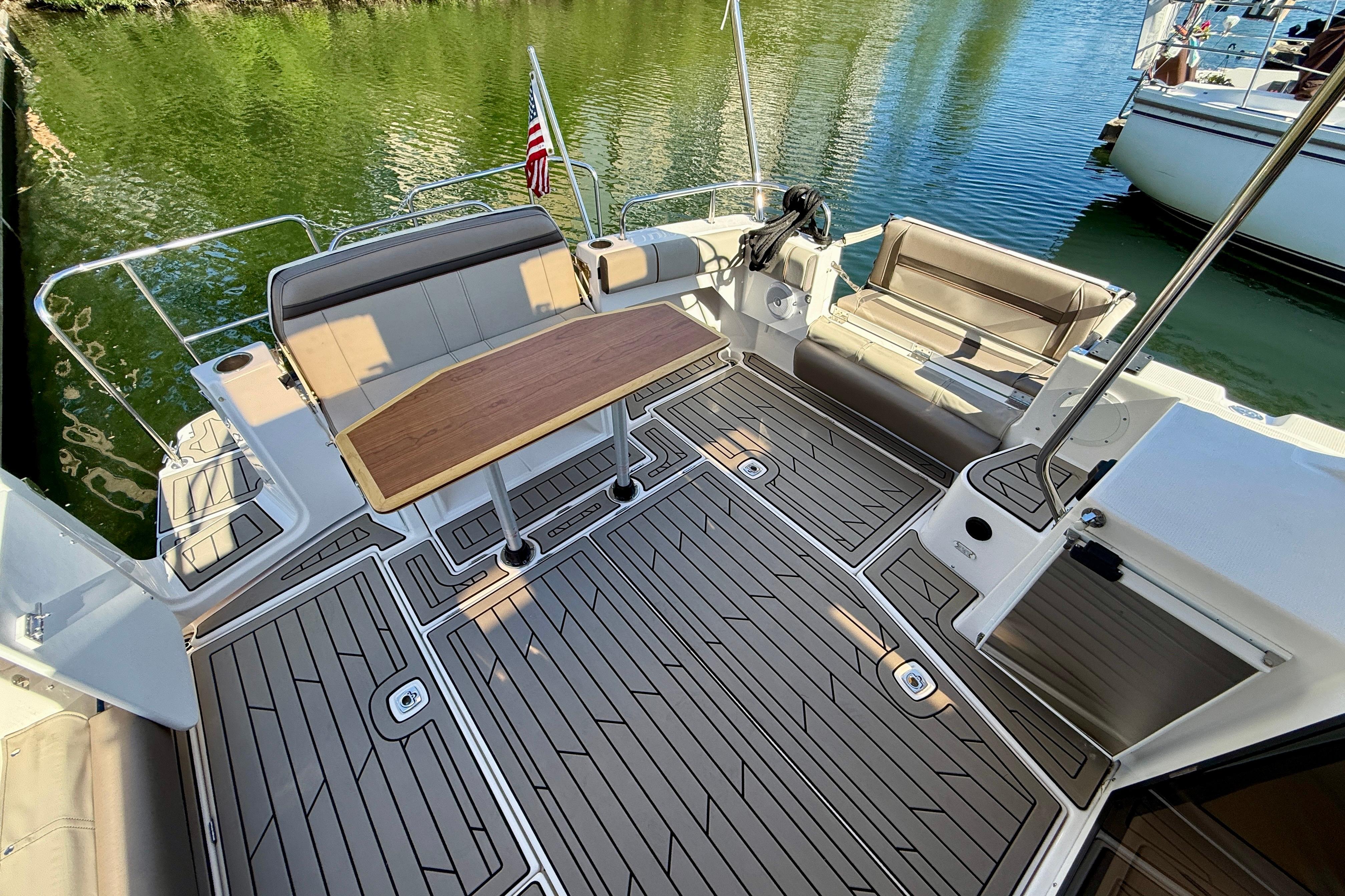 2023 Cutwater C-30 Sedan boat deck with seating and table, docked on calm water.