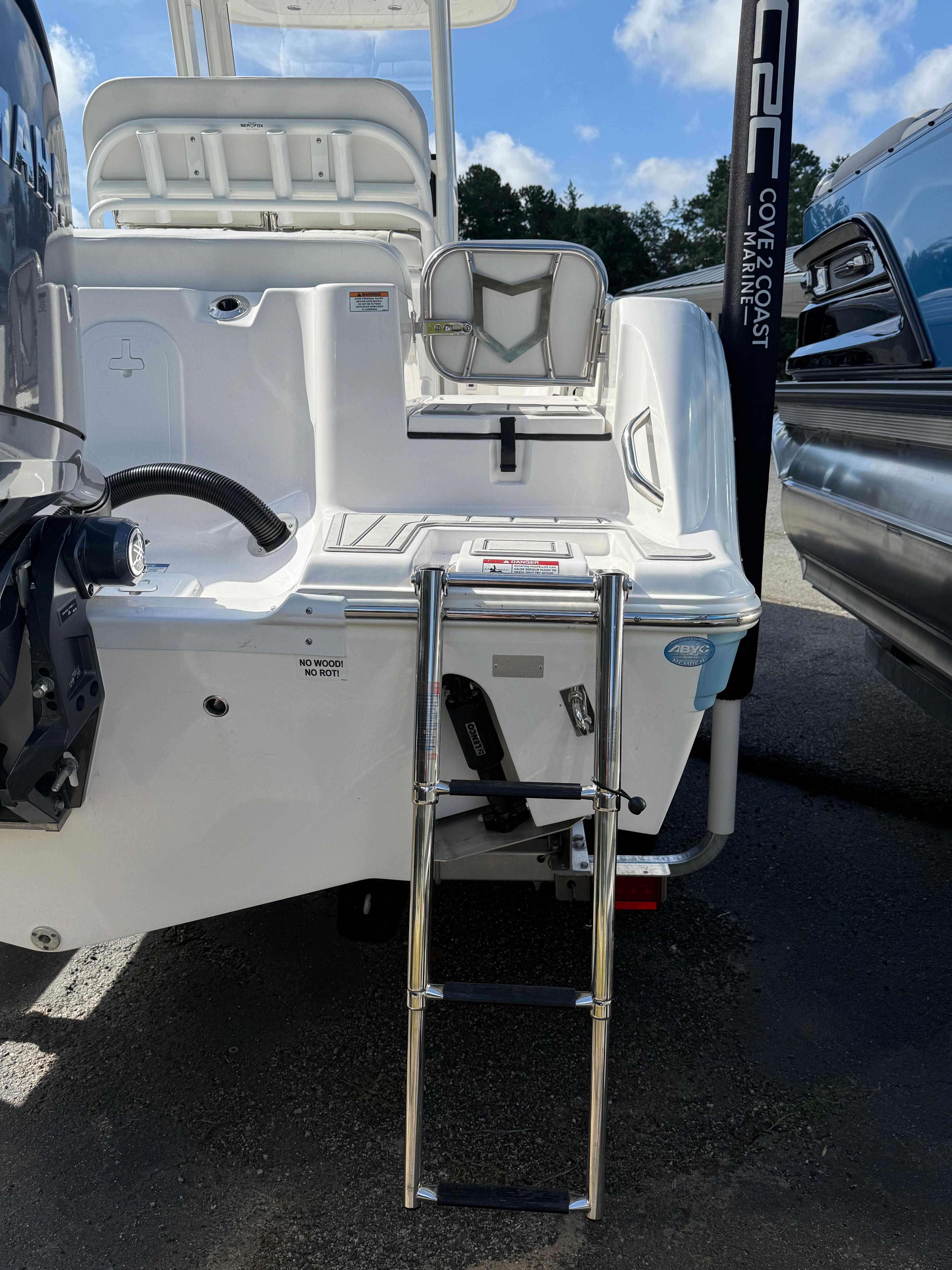 2026 Sea Fox 228 Commander boat with ladder and engine, parked outdoors.