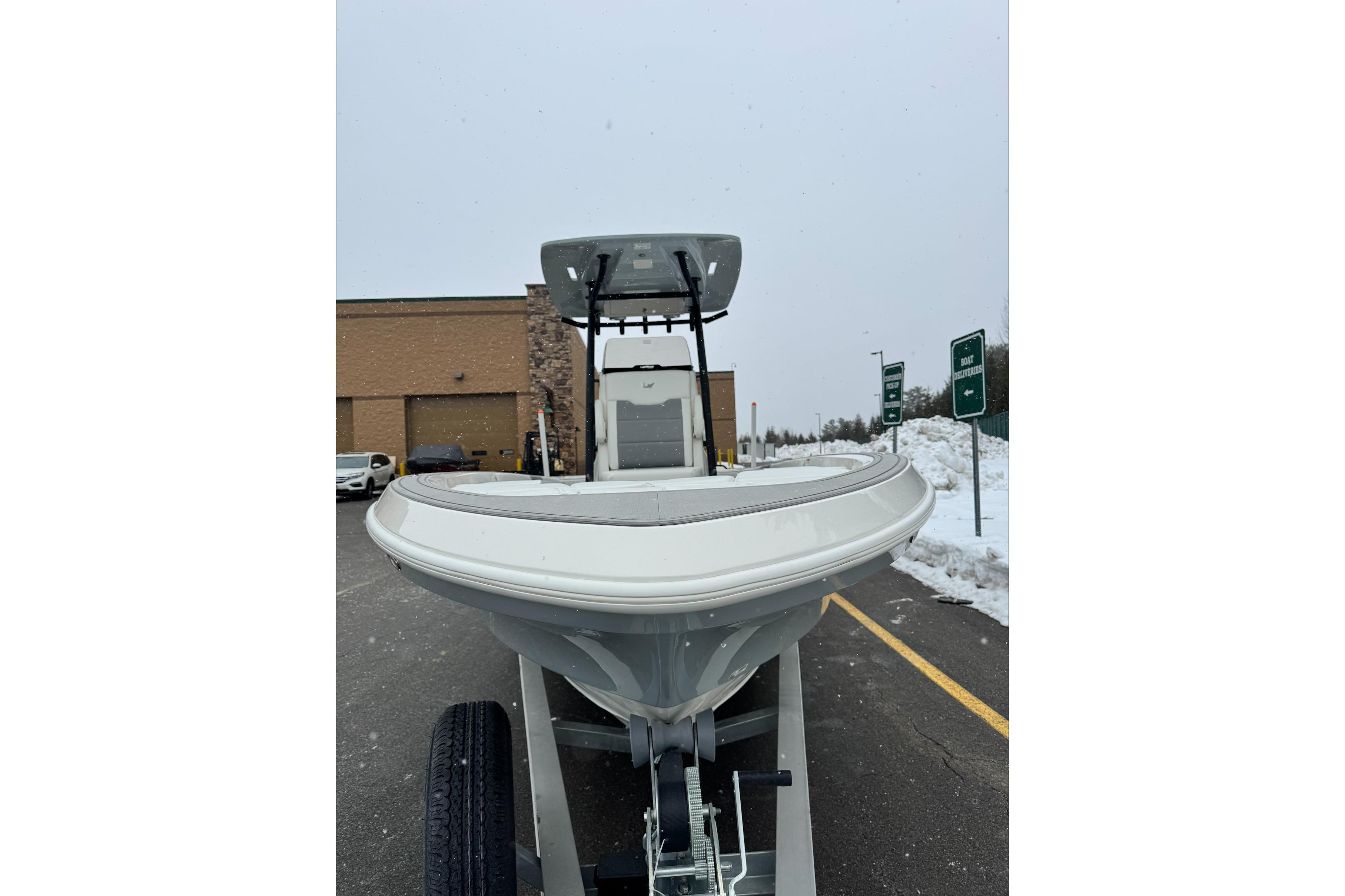 2026 Mako 24 APEX boat on trailer in snowy parking lot.