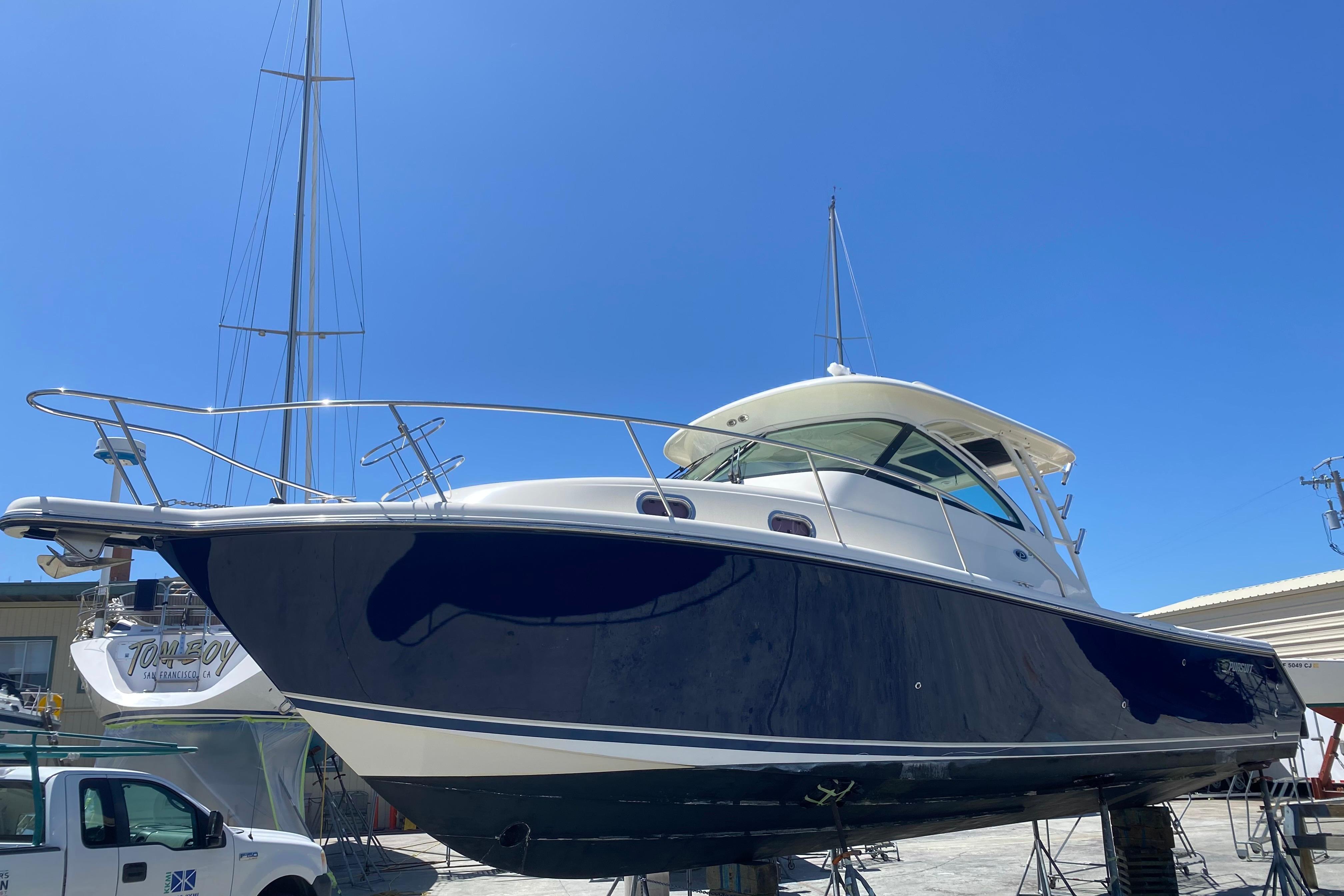 2014 Pursuit OS 345 Offshore boat on dry dock under clear blue sky.