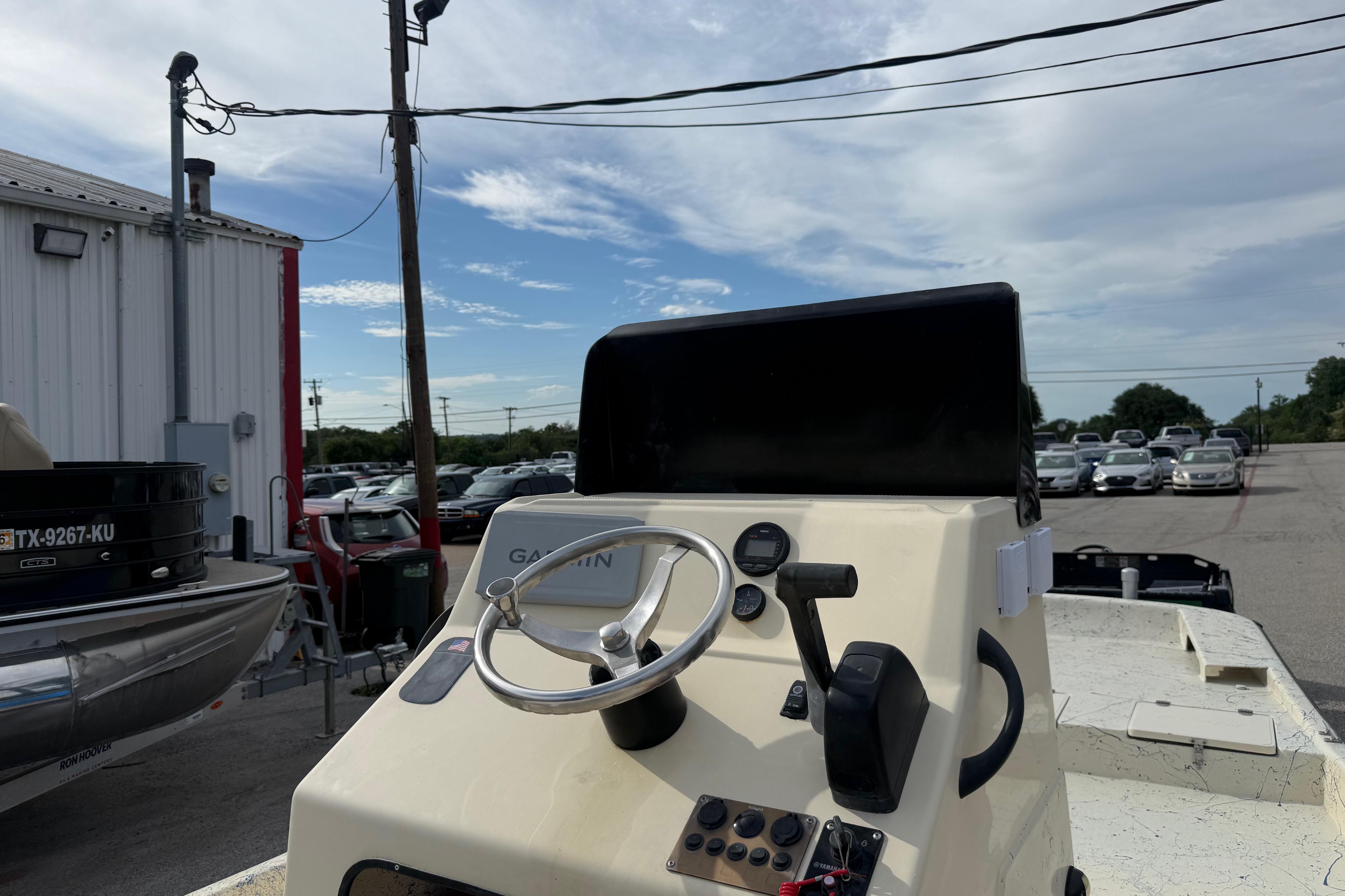 2007 Flats Cat 19 boat dashboard with steering wheel and controls, parked outdoors.