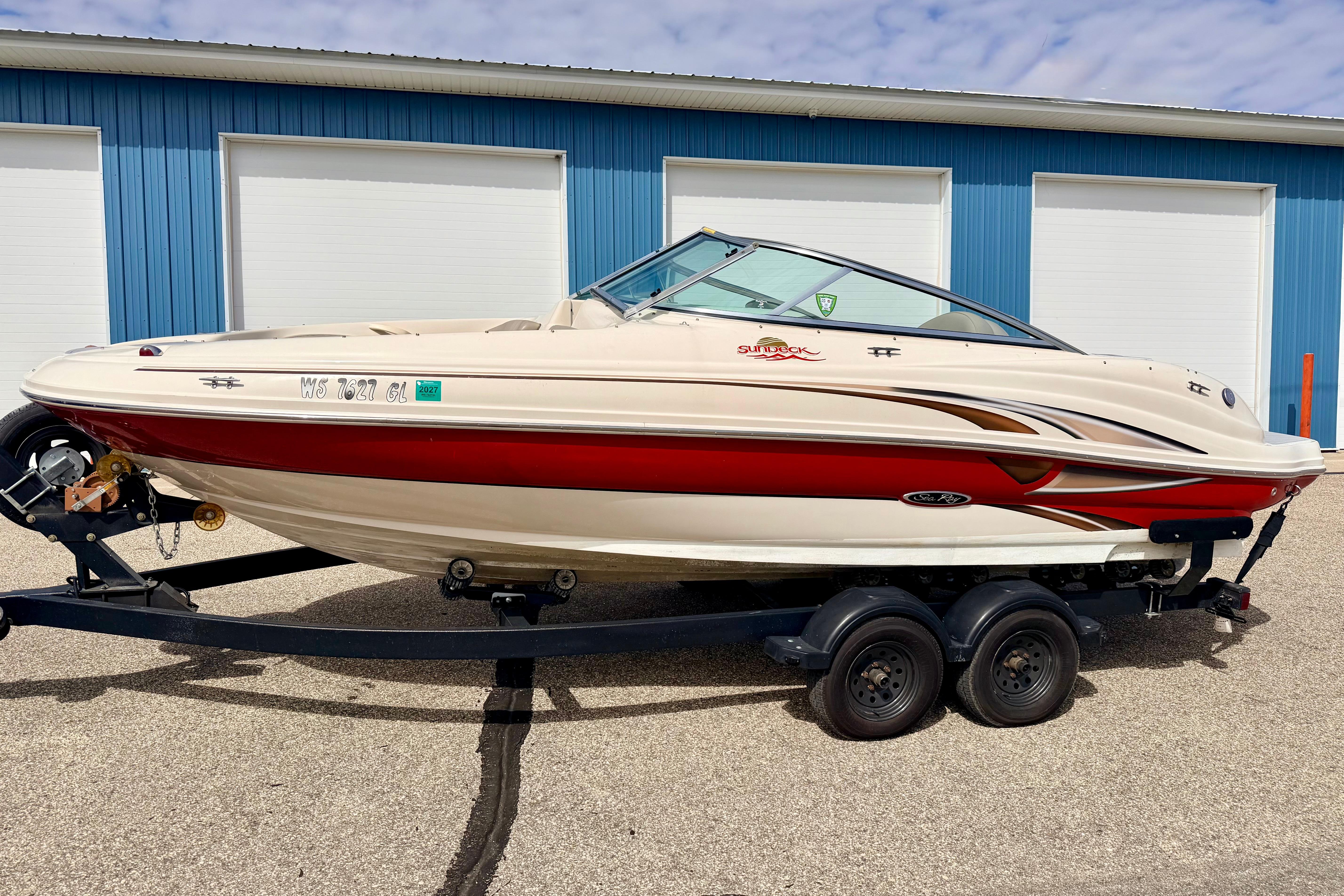 2003 Sea Ray 200 Sundeck boat on trailer, parked outside blue building.